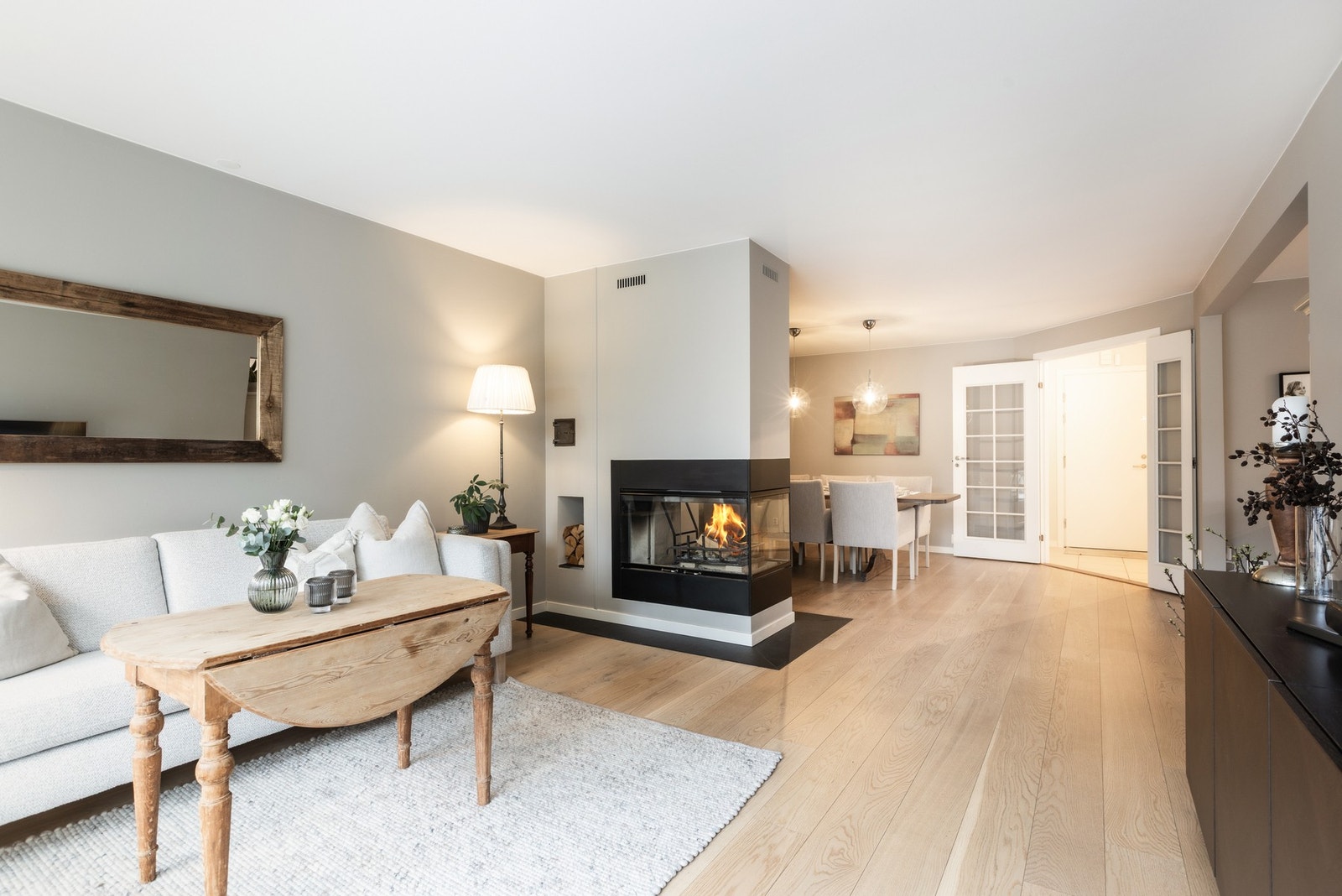 Lys stue med peis og spiseplass. Romslig planløsning med åpen tilgang via doble dører til entreen. Galleribilde