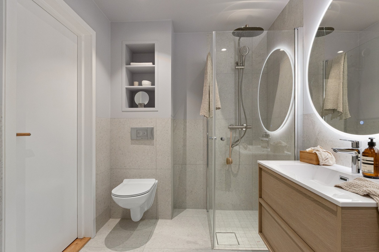 Badet er utstyrt med varmekabler i gulv, stilren baderomsinnredning og regnfallsdusj Galleribilde