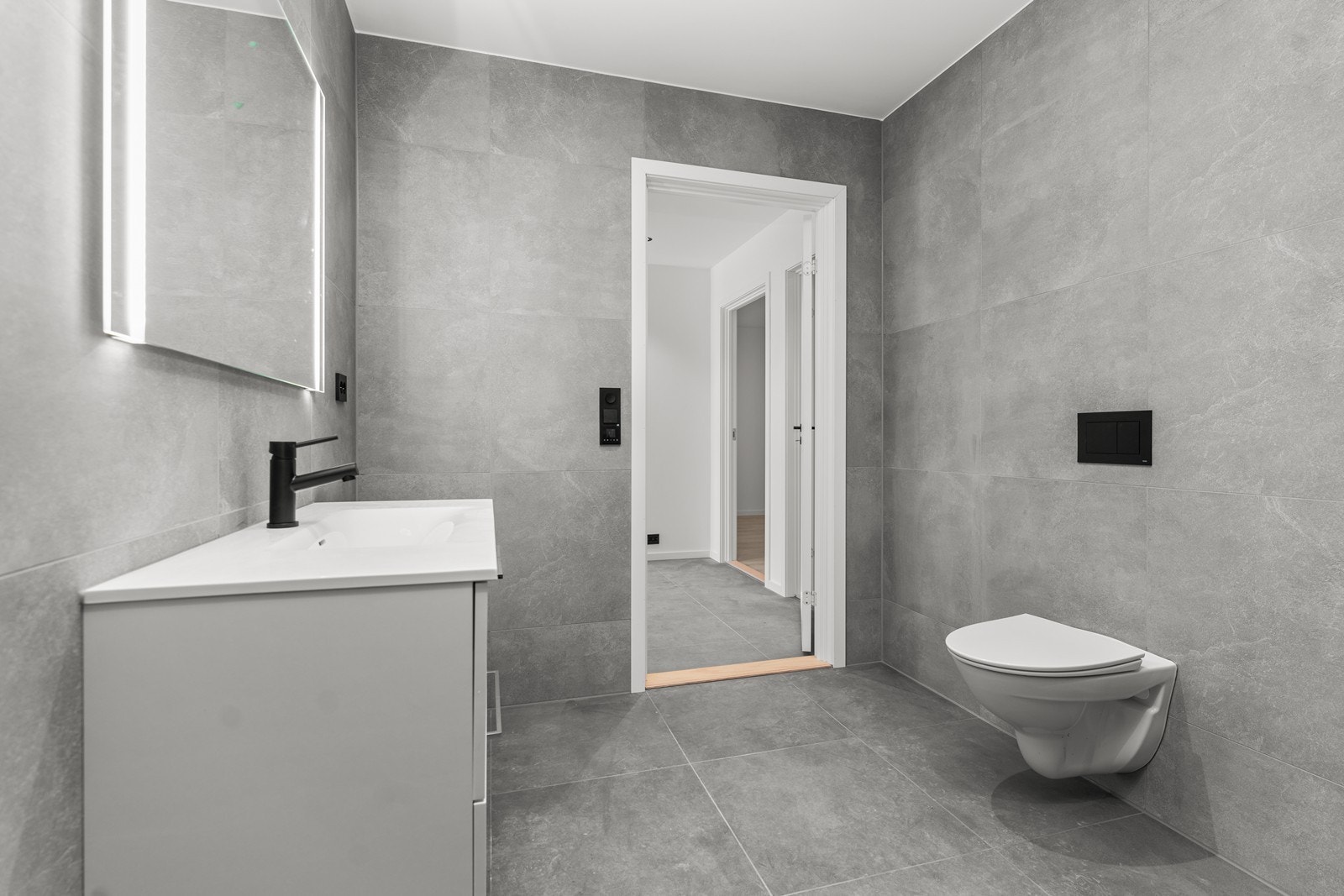 Her er varmekabler i gulv og rommet inneholder vegghengt toalett, dusjhjørne og innredning med nedfelt servant. Galleribilde