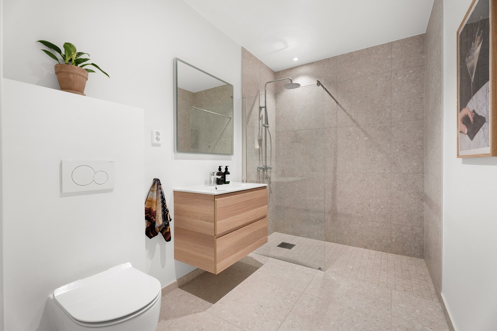 Badet i nedre plan er innredet med et vegghengt klosett, en servant nedfelt i baderomsinnredningen og et dusjhjørne med glassvegg. Galleribilde