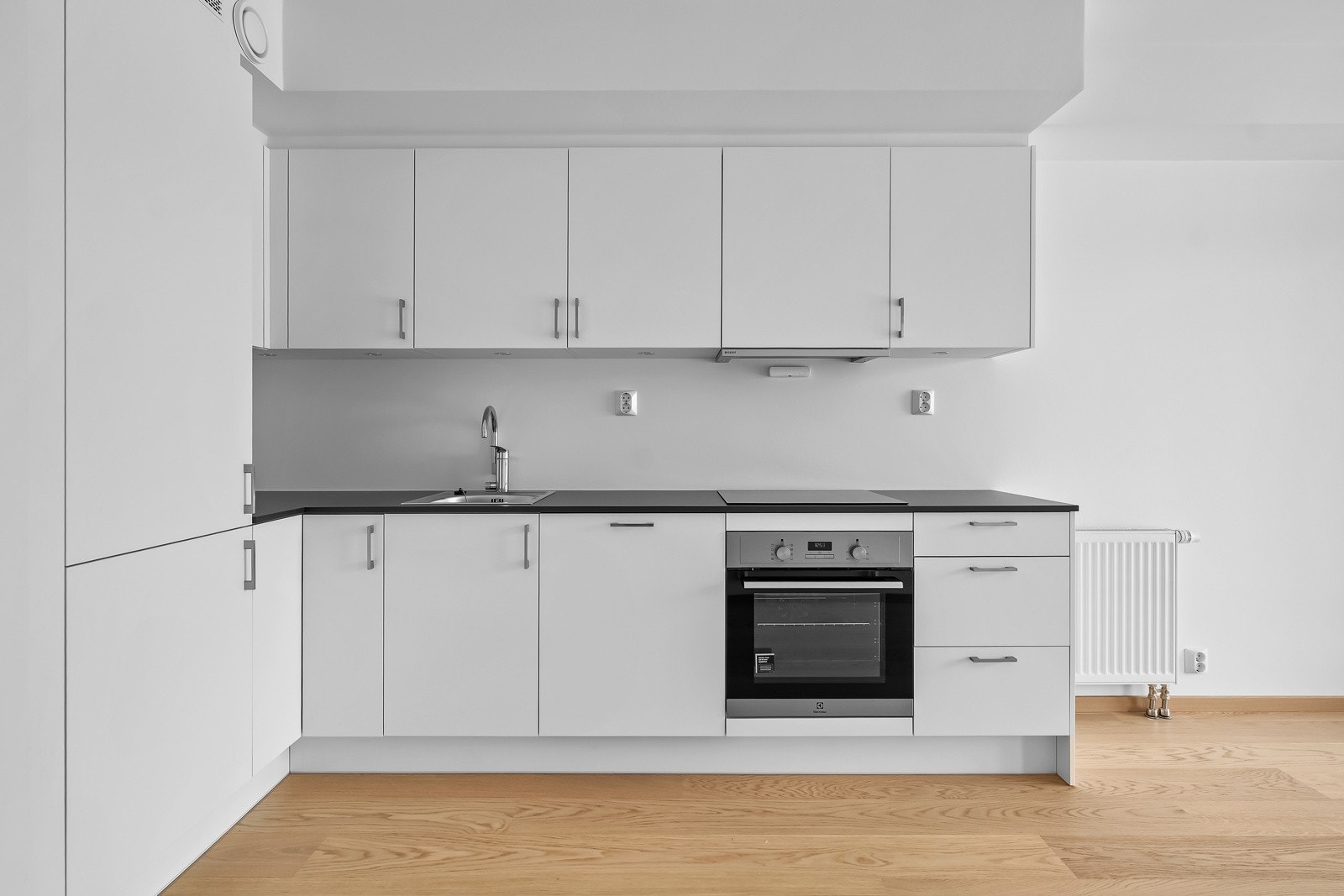 Lekkert kjøkken utformet i vinkel, med integrerte hvitevarer. Galleribilde