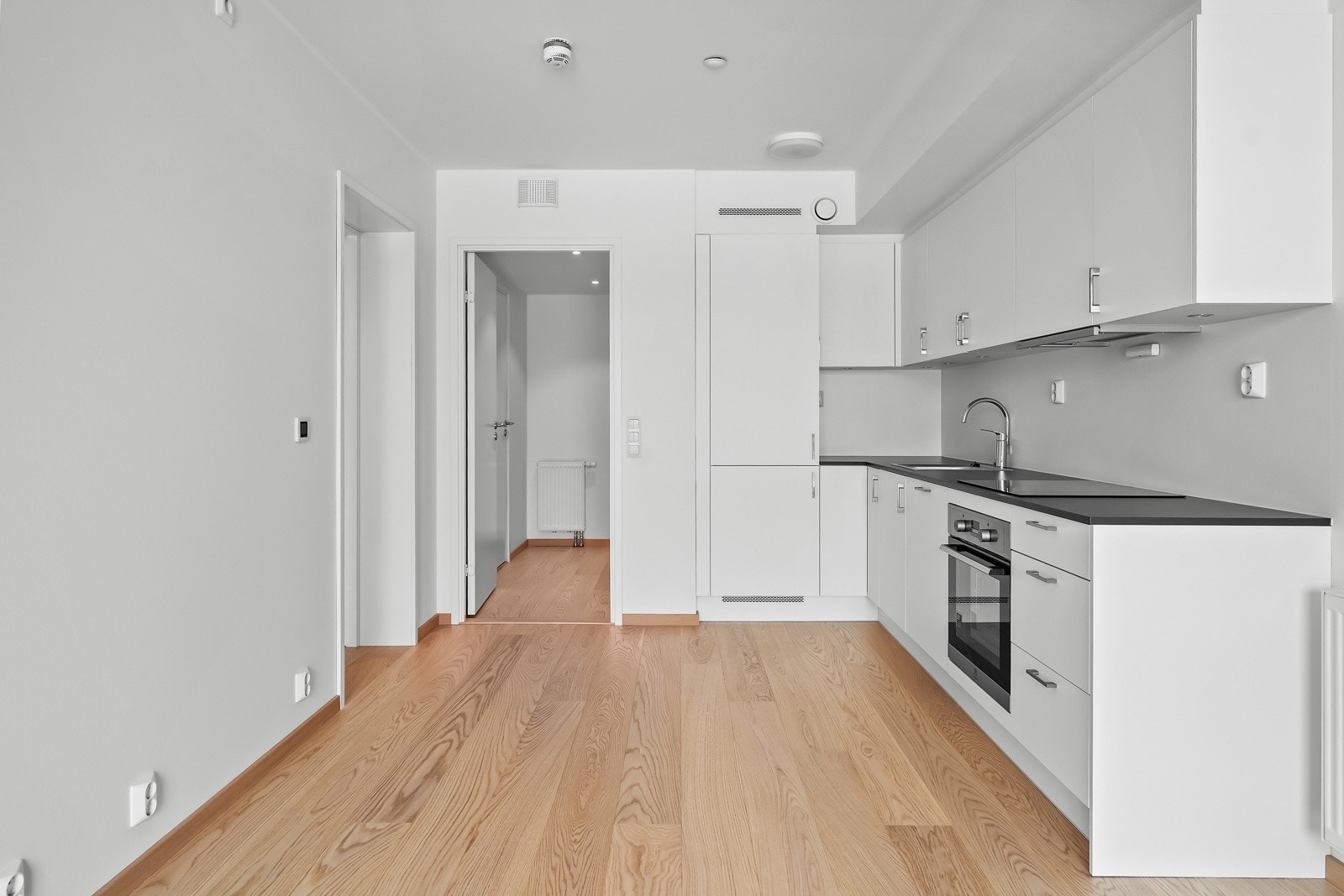 Lekkert kjøkken utformet i vinkel, med integrerte hvitevarer. Galleribilde