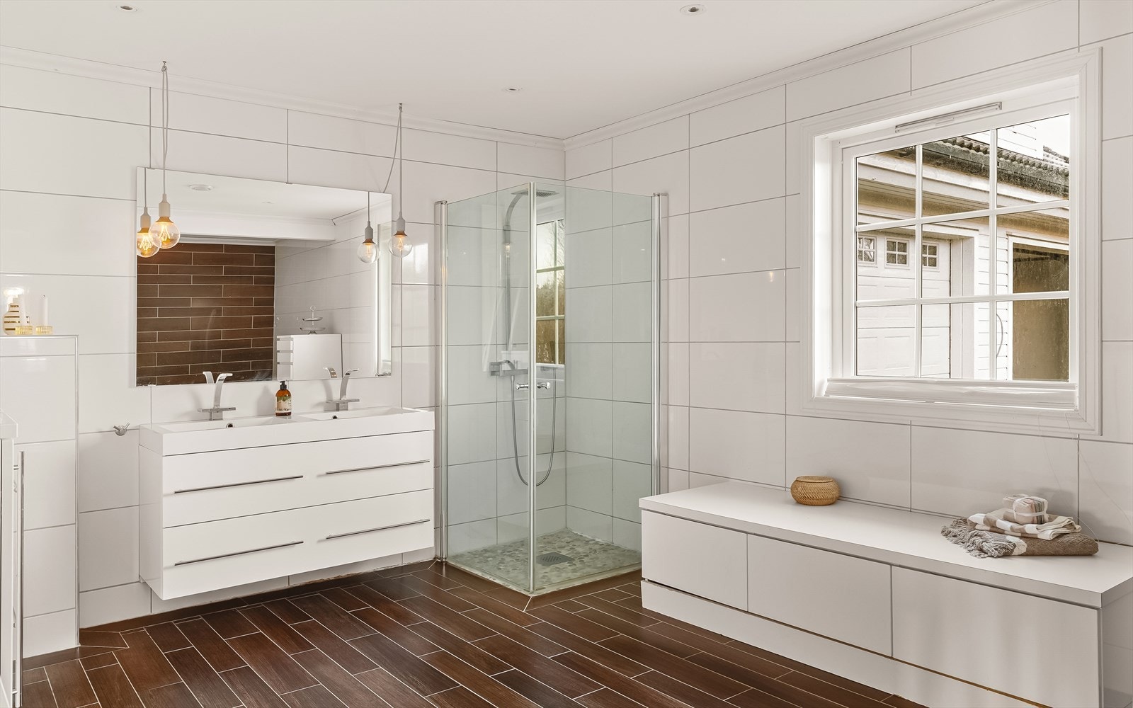 Innredet med dobbel vask, skuffeseksjon, innfellbare dusjdører i glass, vegghengt toalett og vegghengt skap. Galleribilde