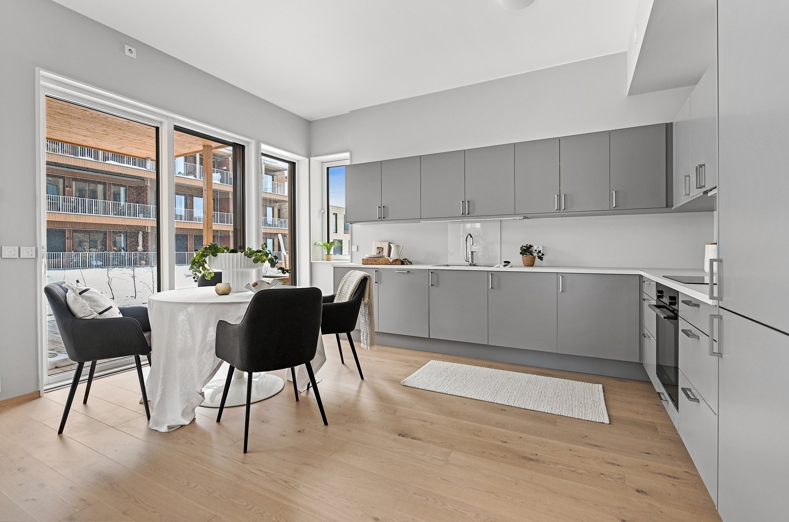 Kjøkken og spiseområde med gjennomført design, rikelig skapplass og store vinduer rundt en hyggelig spiseplass. Galleribilde