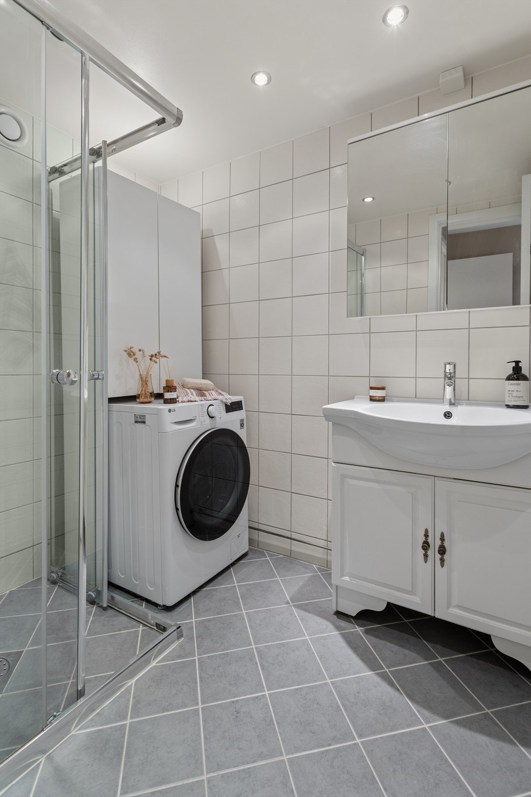 Badet har flislagt gulv med elektriske varmekabler, dusjhjørne med innfellbare vegger og opplegg for vaskemaskin. Galleribilde