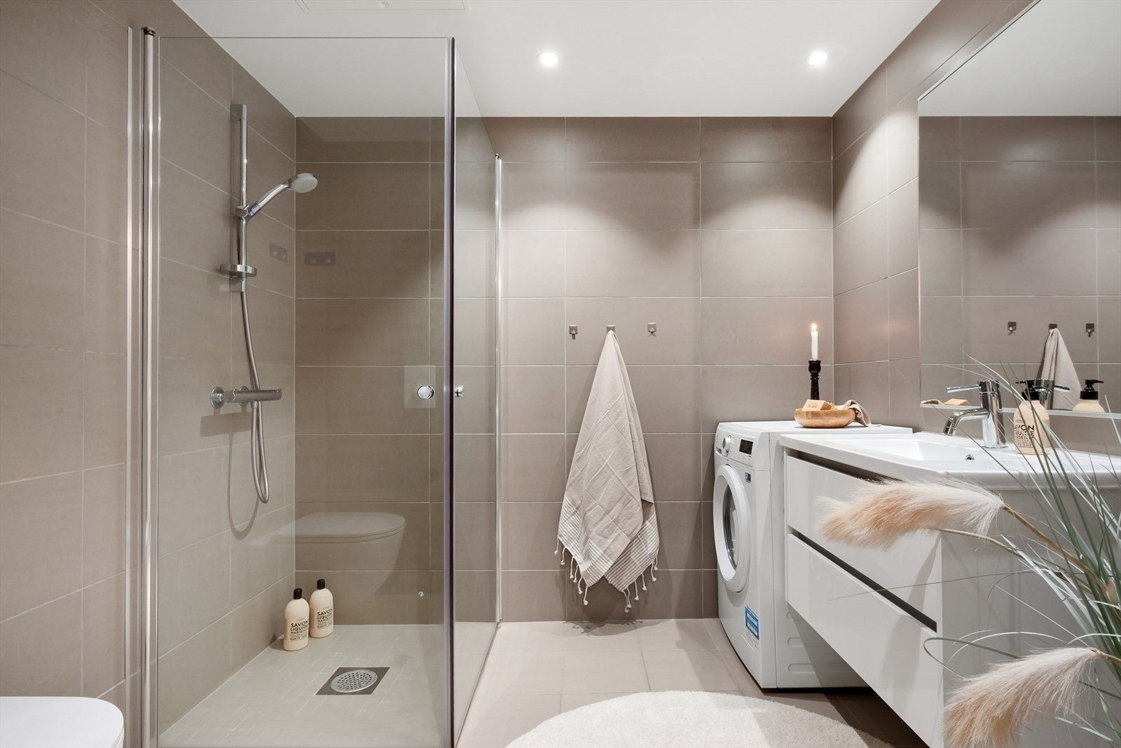 Det har et stort dusjhjørne og fliser i en pen beigefarge som gir rommet et lunt og tidløst uttrykk. Galleribilde