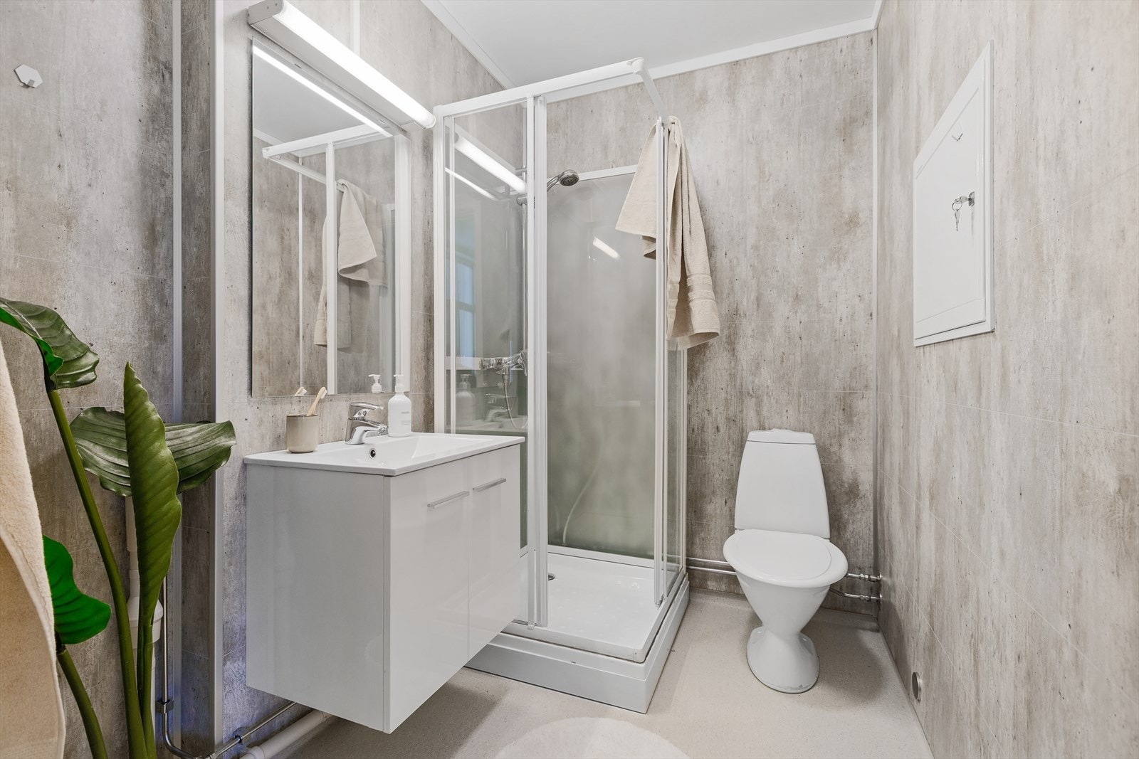 Baderommet er innredet med nedfelt servant, veggspeil med lysarmatur og el-uttak, gulvmontert toalett og dusjkabinett. Galleribilde