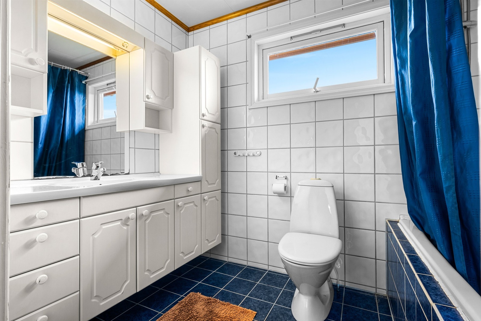 Romslig baderom med gulvstående toalett og servant. Galleribilde