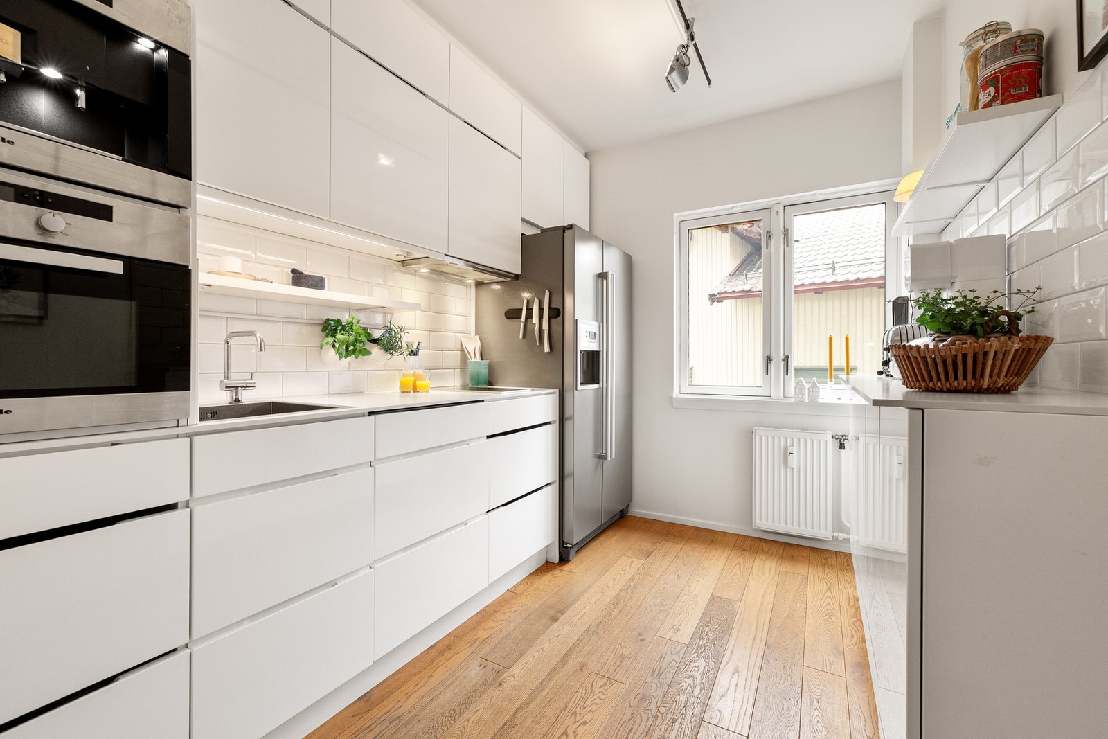 Kjøkkenet har en moderne innredning med hvite, glatte fronter som gir et stilrent og tidløst uttrykk. Galleribilde