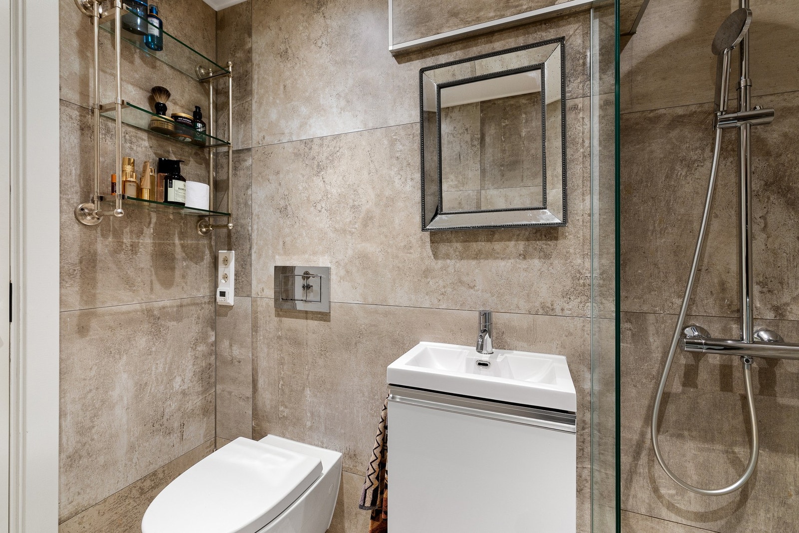 Badet er innredet med veggmontert toalett, servantinnredning med nedfelt servant og speil over. Videre er det dusjsone avskjermet med glassvegger samt opplegg for vaskemaskin. Galleribilde