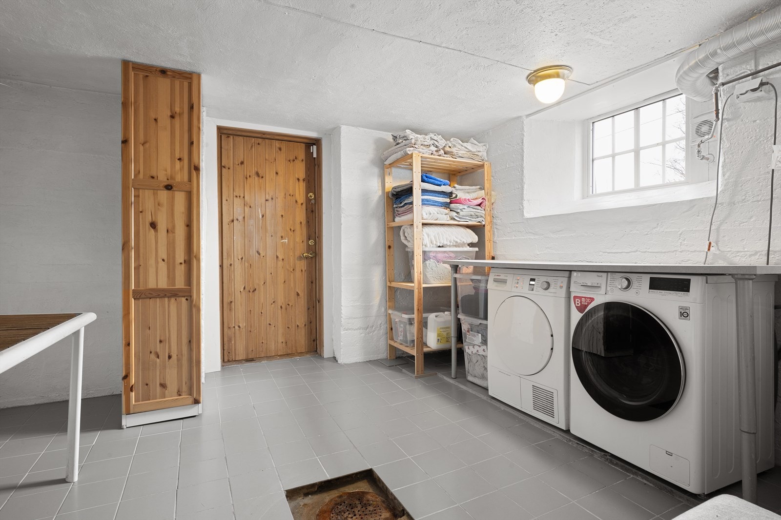 Vaskerom med flislagt gulv, sluk og opplegg for vaskemaskin og tørketrommel. Galleribilde