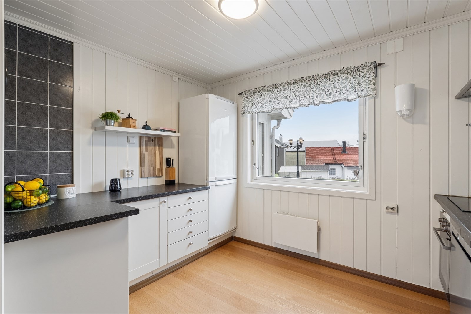 Kjøkkenet har en pen og tidløs IKEA-innredning med hvite profilerte fronter og laminatbenkeplate med 1 1/2 vaskekum i stål. Galleribilde