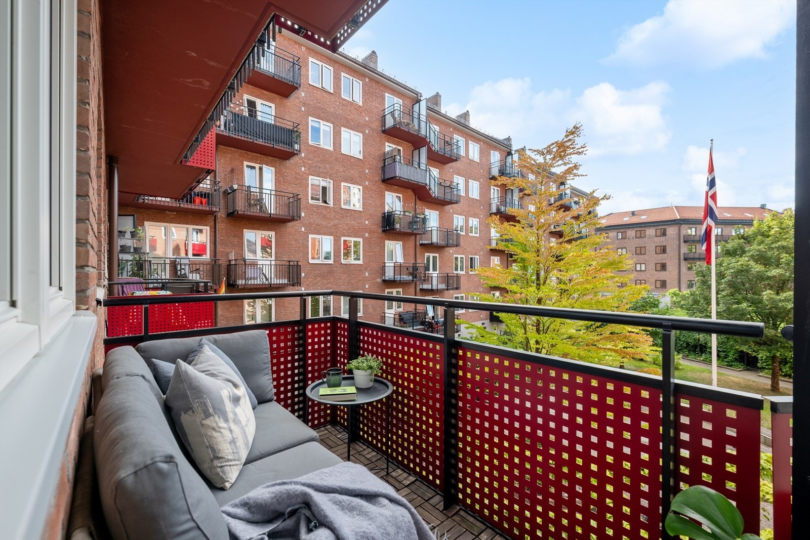 Solrik balkong vendt mot en grønn og skjermet bakgård - et rolig uteområde rett utenfor stuedøren. Galleribilde