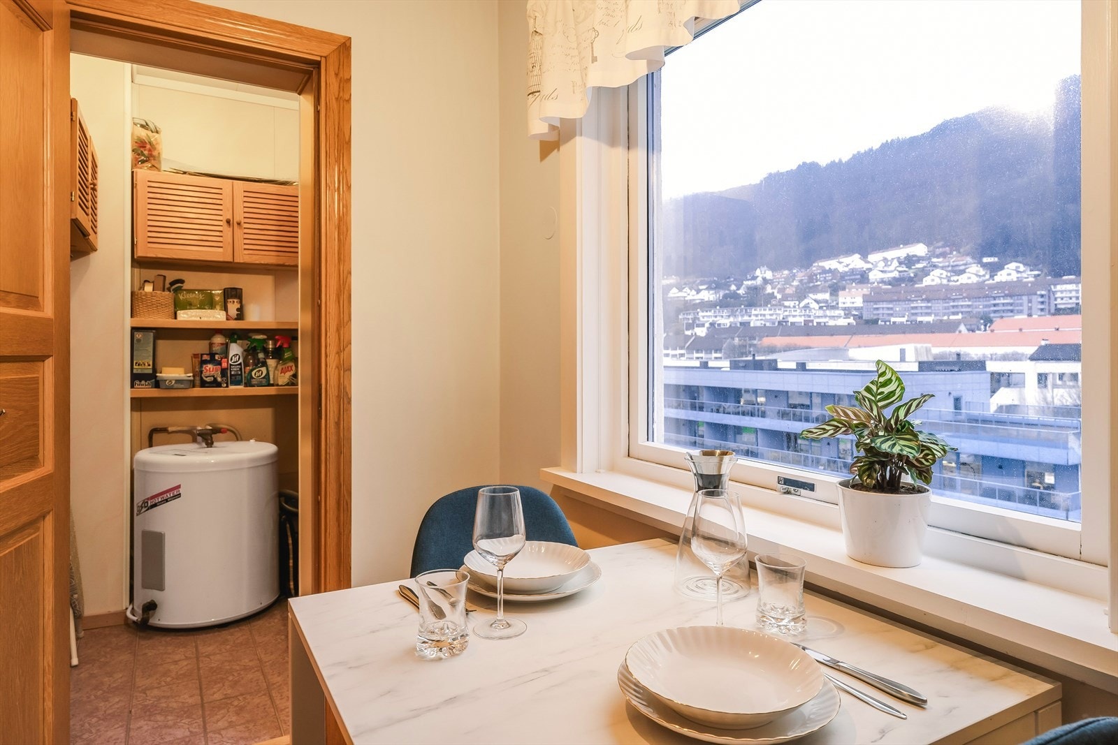 Fra kjøkkenet er det utsikt utover nærområdet og oppover Landåsfjellet. Det er også inngang til en praktisk oppbevaringsbod på 1,9 kvm. Boden er innredet med vamrtvannstank (Oso Hotwater, 1996, 116 Liter), overskap og diverse hyller for enkel lagring. Galleribilde