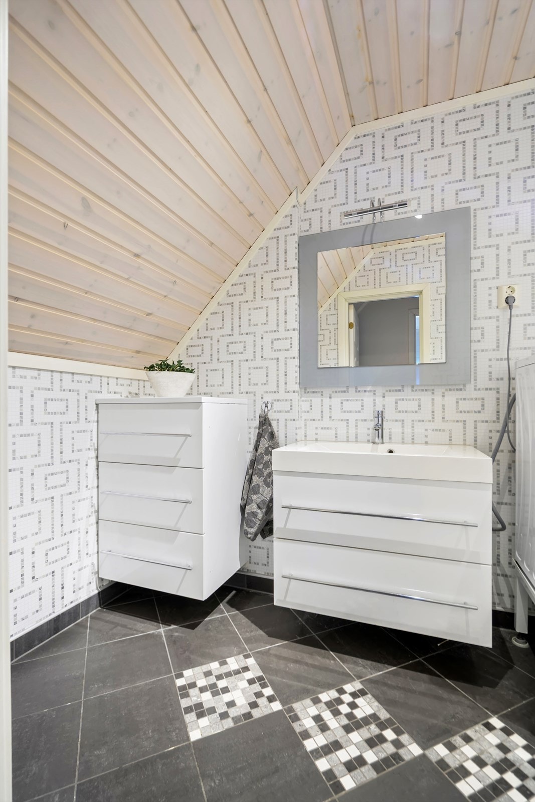 Rommet har flis på gulv, våtromsplater på vegg og trepanel i tak. Det er opplegg for vaskemaskin, toalett og servant med underskap. Galleribilde