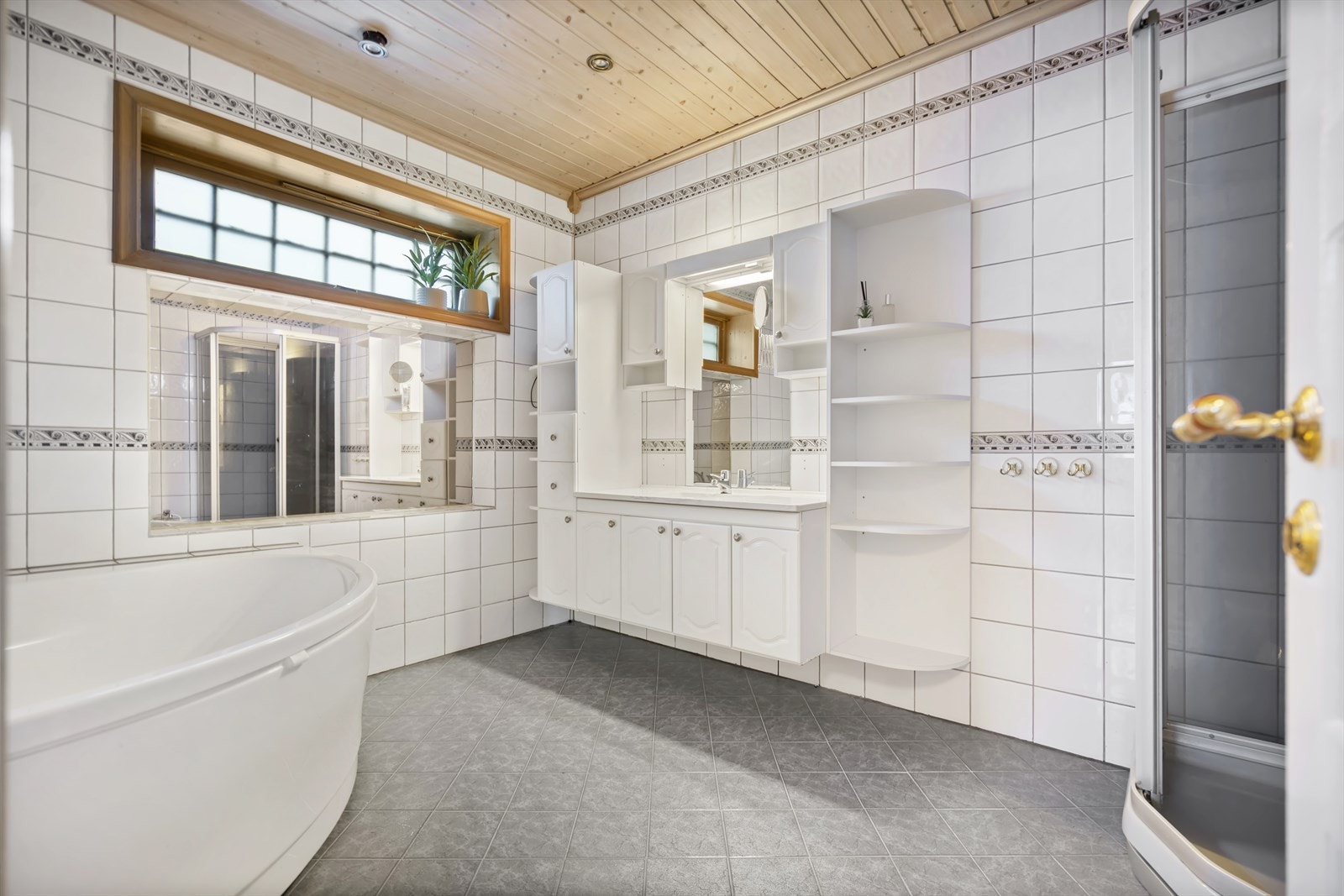 Romslig flislagt bad med spotter i tak. Rommet har badekar, dusjkabinett, toalett, bide og baderomsinnredning med heldekkende servant. Galleribilde