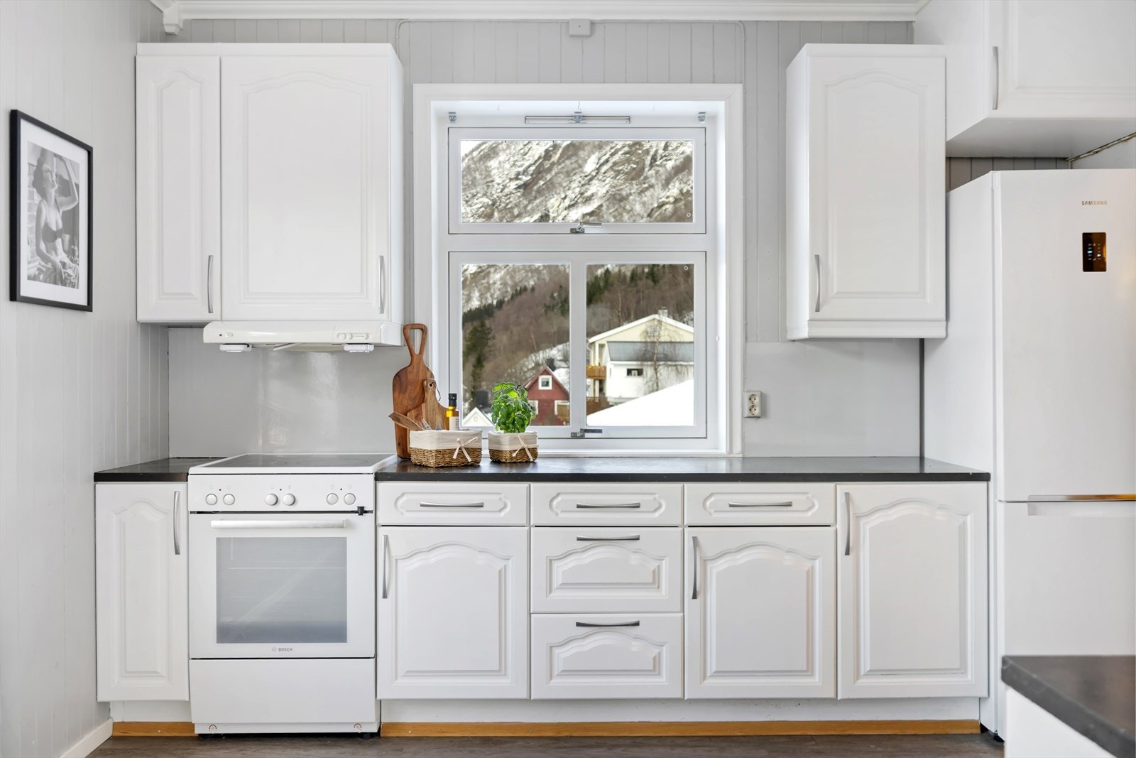 Kjøkkenet har lyse profilerte fronter og benkeplate av laminat, kjøkkenventilator med avtrekk ut. Galleribilde