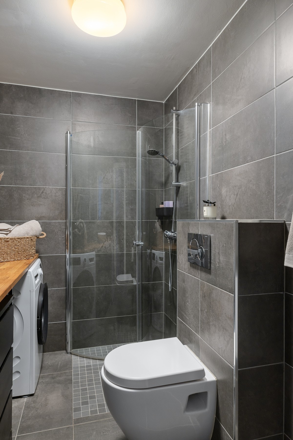 Baderommet har moderne baderomsinnredning, benkeplate med servant, dusjhjørne med innfellbare dusjdører og opplegg for vaskemaskin. Galleribilde