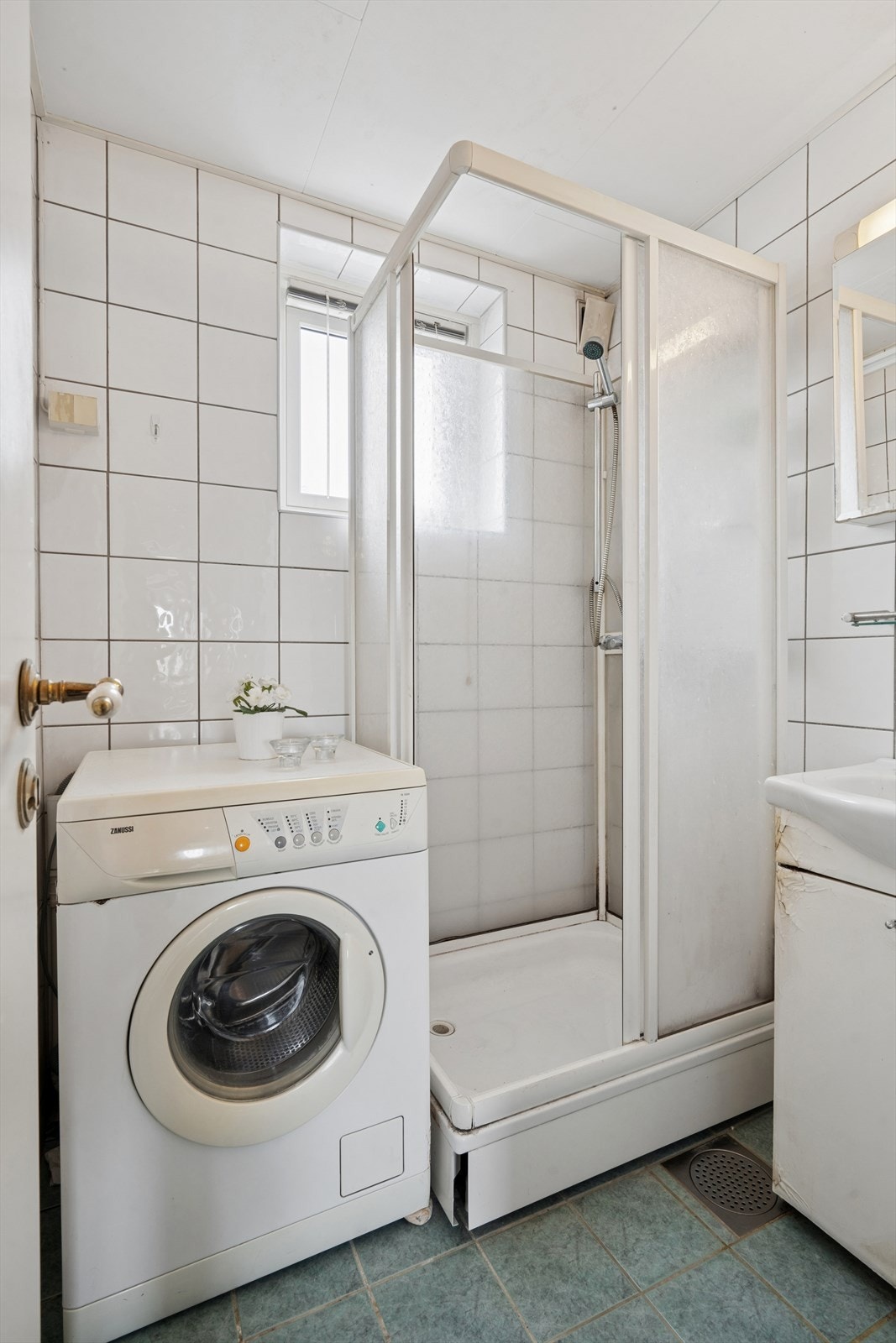 Badet har fliser på vegger og gulv og er utstyrt med dusjkabinett, servant og opplegg for vaskemaskin. Galleribilde