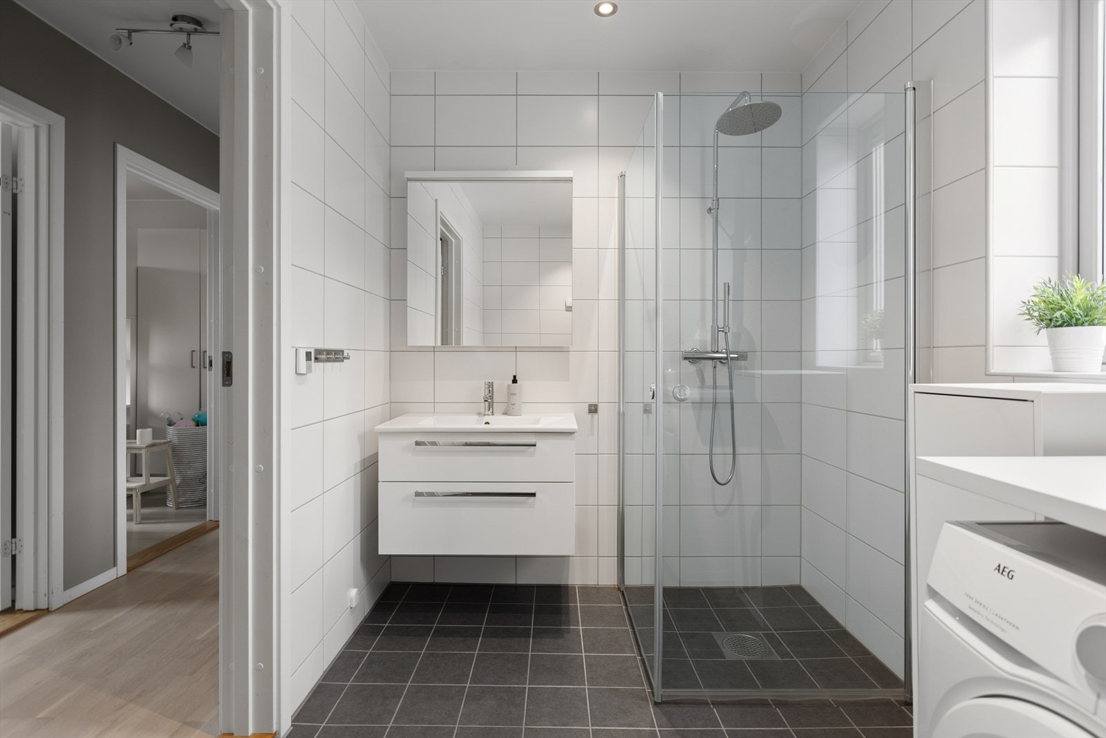 Helfliset baderom i 2. etasje. Rommet er utstyrt med servant med underskuffer, dusjhjørne, toalett og opplegg for vaskemaskin og tørketrommel. Galleribilde