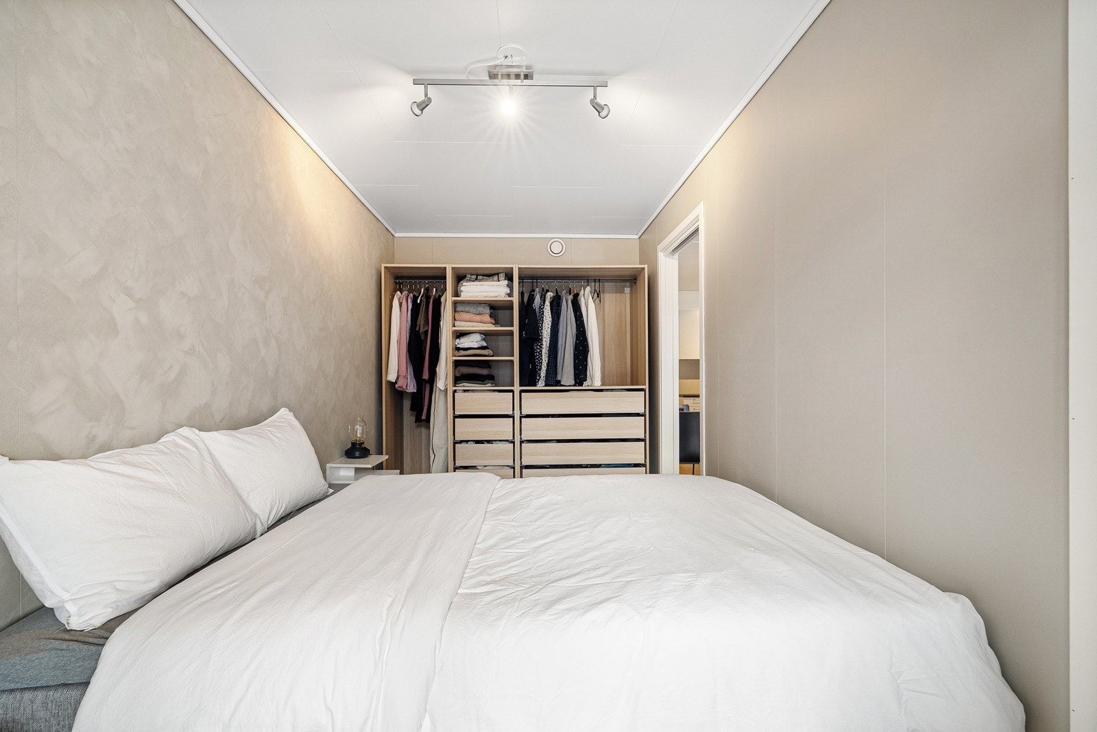 Den åpne garderoben fungerer som en naturlig del av rommet og sørger for god plass til både hengende klær og skuffer Galleribilde