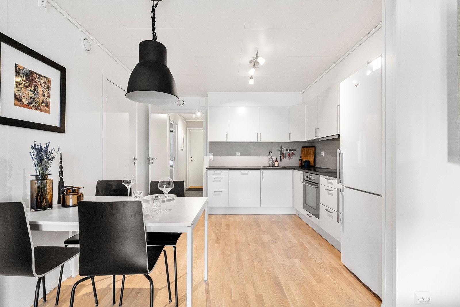 Kjøkkenet er praktisk utformet i L-form, noe som maksimerer romfølelsen. Her får du en effektiv arbeidssone med rikelig av skap- og benkeplass, perfekt for hverdagens matlaging. Galleribilde