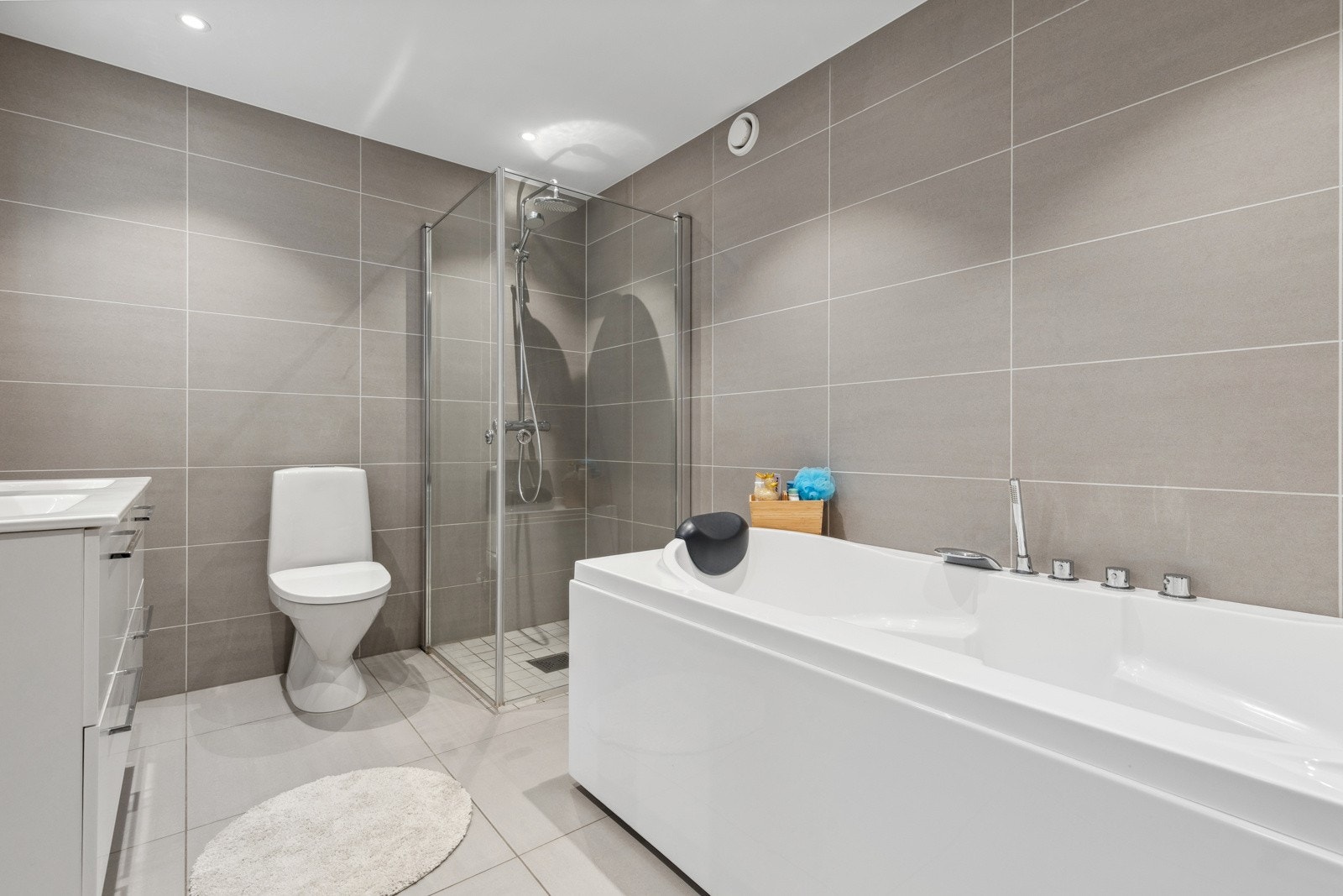 Videre har badet et separat dusjhjørne med regnfallsdusj og innfellbare dusjdører i glass, samt frittstående badekar - perfekt for en familie. Galleribilde