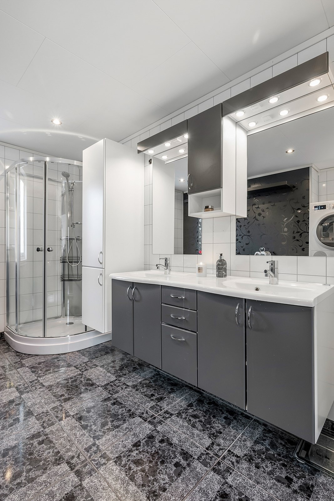 Badet ble oppgradert i 2010 og byr på et delikat uttrykk, med dusjkabinett, opplegg for vaskemaskin og rikelig med oppbevaring. Til info: Skapet mellom speilene og det hvite høyskapet er fjernet etter at bildene ble tatt. Galleribilde