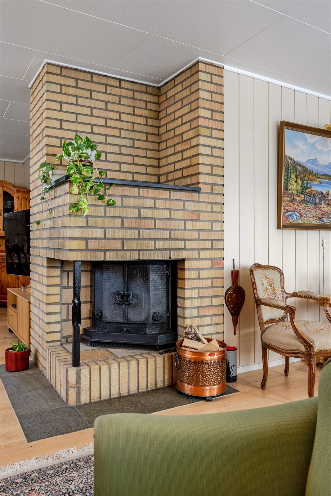 Som et fint midtpunkt i stuen er det en koselig murt peis med peisinnsats, som både gir god varme og bidrar til ekstra hygge på kaldere høst- og vinterdager. Galleribilde