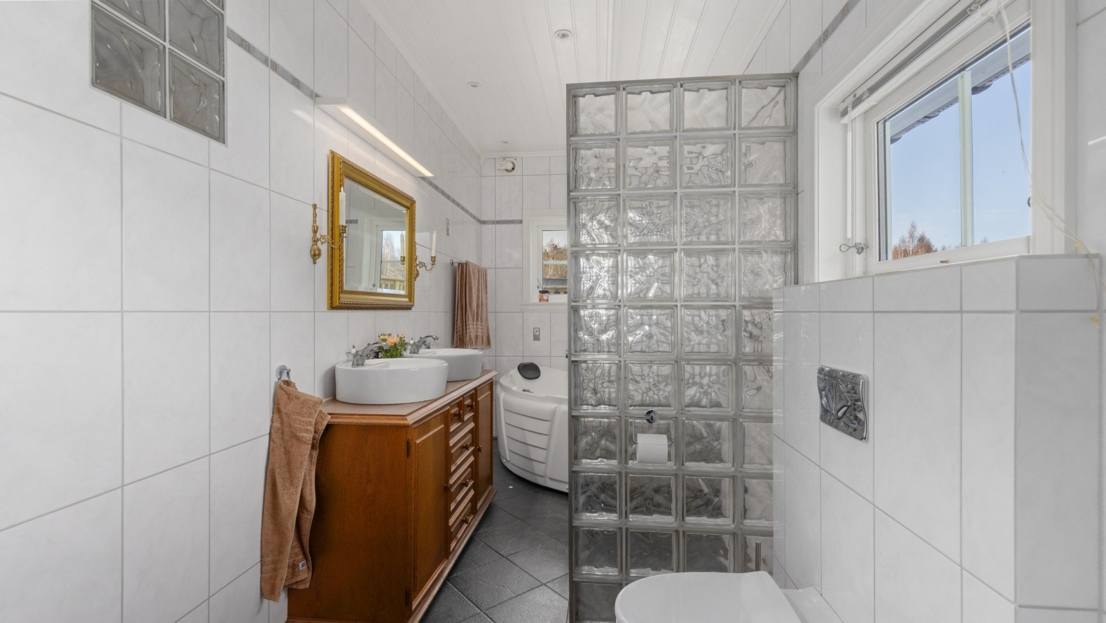 Like ved entréen er det lyst flislagt bad med bl.a. flott baderomsinnredning med dobbel vask Galleribilde
