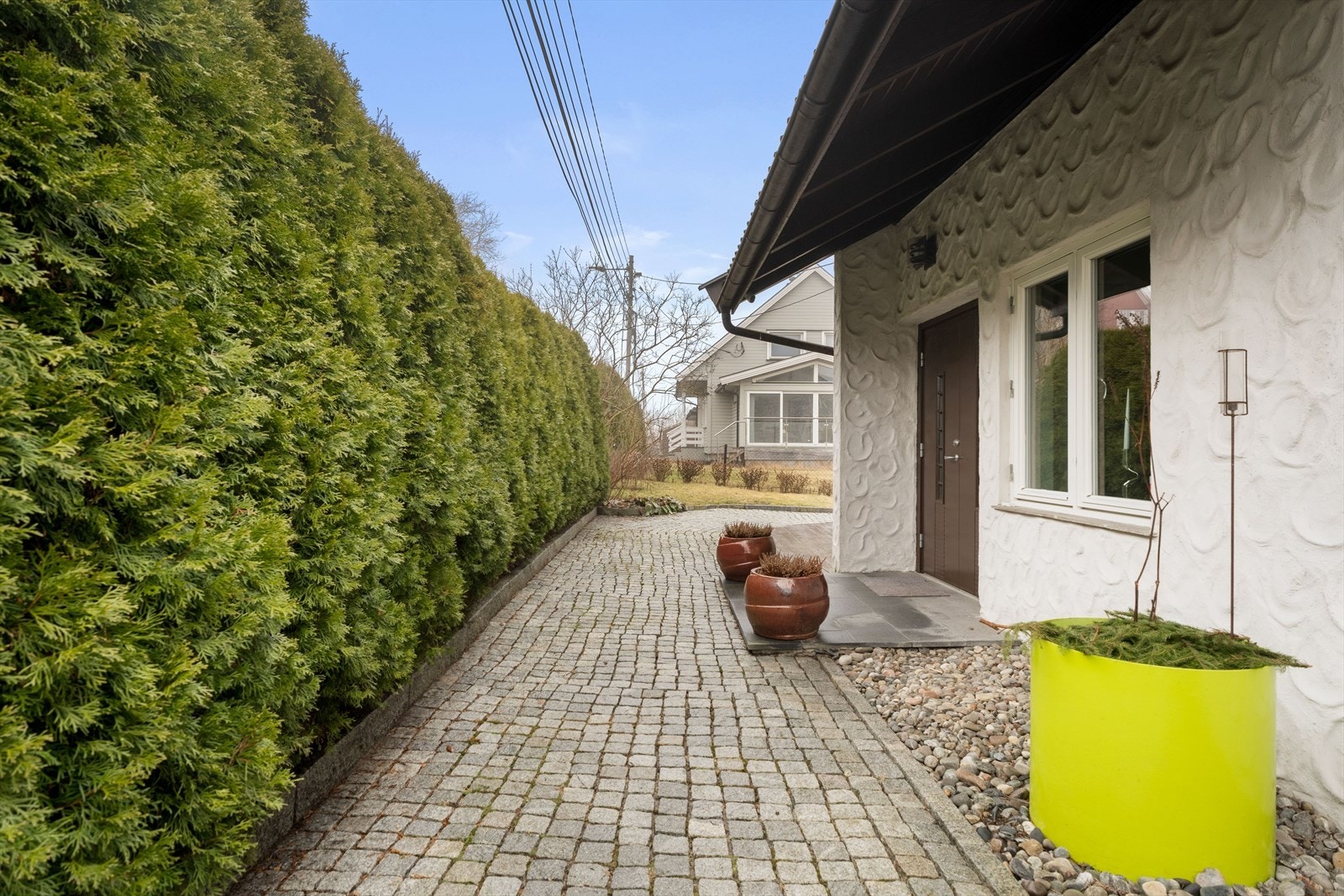 Hekk og beplantning skaper en privat og skjermet adkomst til boligen. Galleribilde