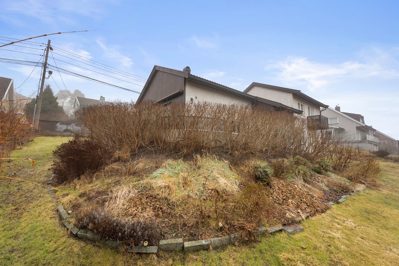 Tomten er pent avgrenset med hekk og beplantning. Galleribilde