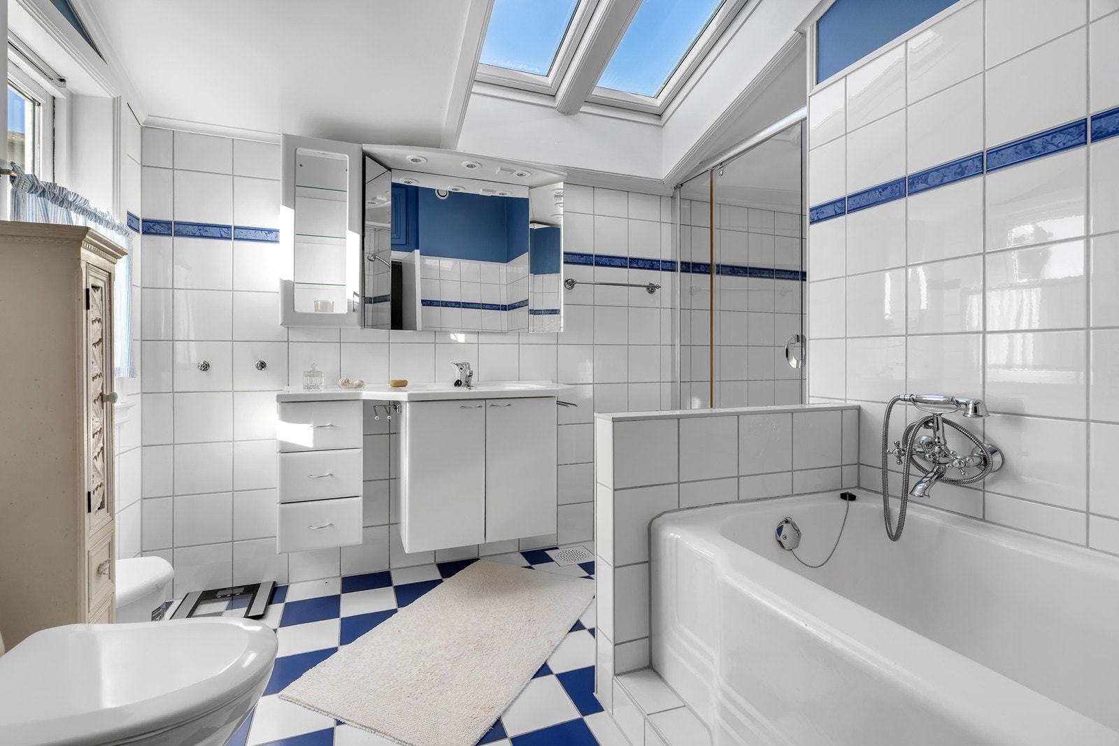 Bad i 2.etg utstyrt med dusj, badekar, toalett og servant med skap Galleribilde