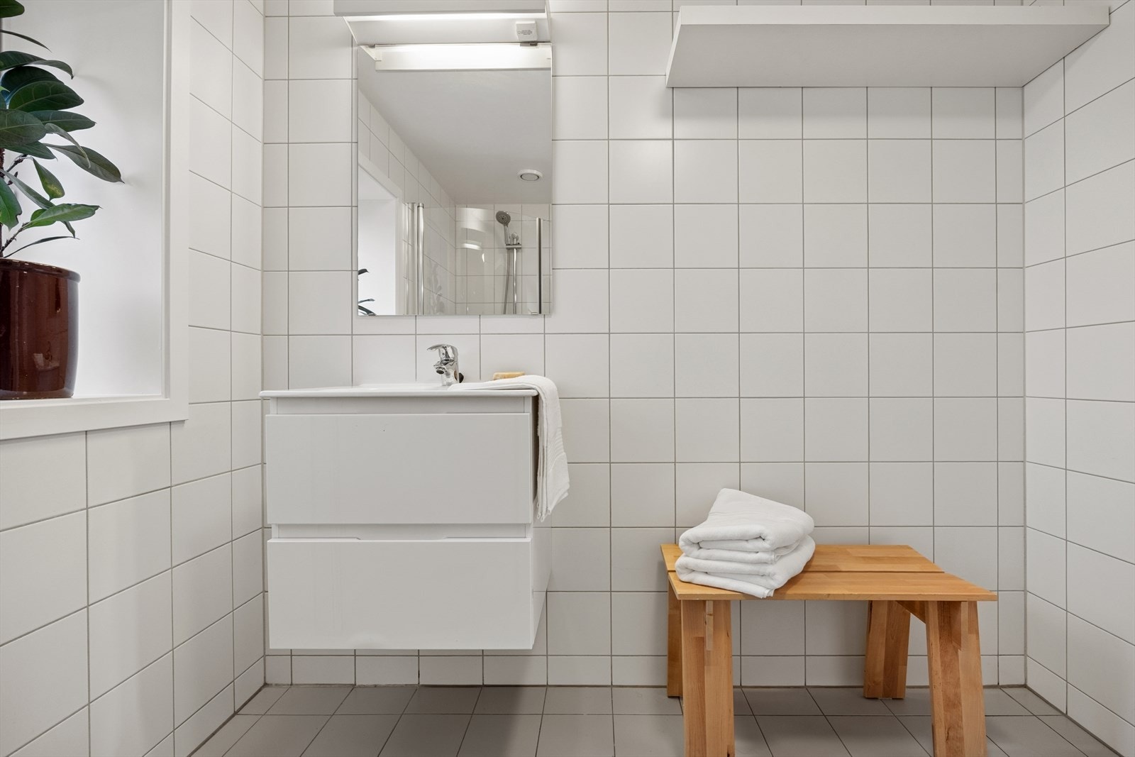 Flislagt baderom med servant, speil og god oppbevaring Galleribilde