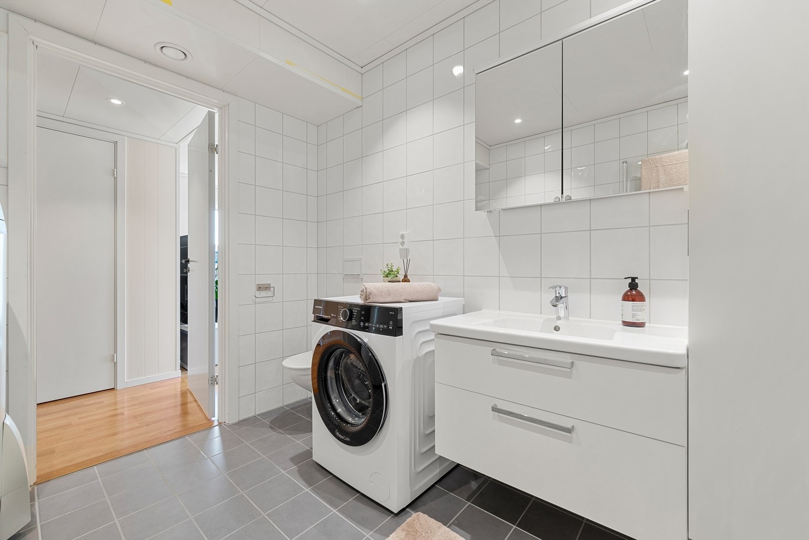 Badet er videre utstyrt med innfellbare dusjdører, vegghengt toalett og opplegg for vaskemaskin/tørketrommel. Galleribilde