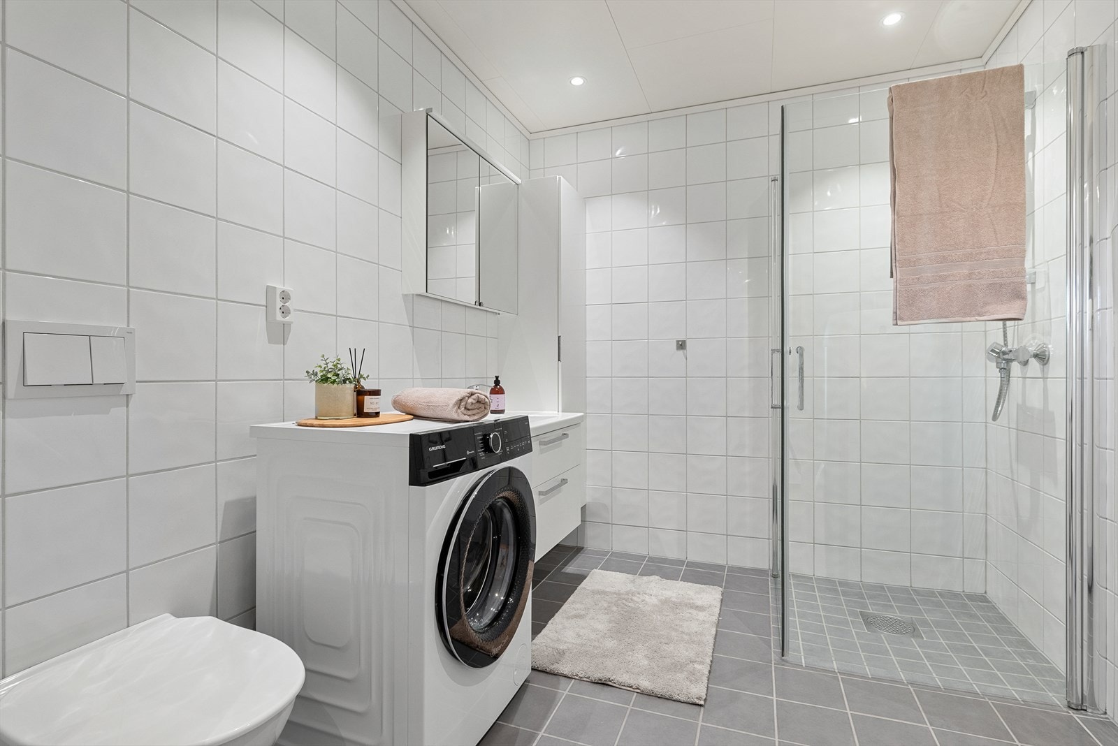 Det 6,5 m² store badet fremstår som innbydende med helflisede overflater, behagelig gulvvarme og downlights i tak. Galleribilde