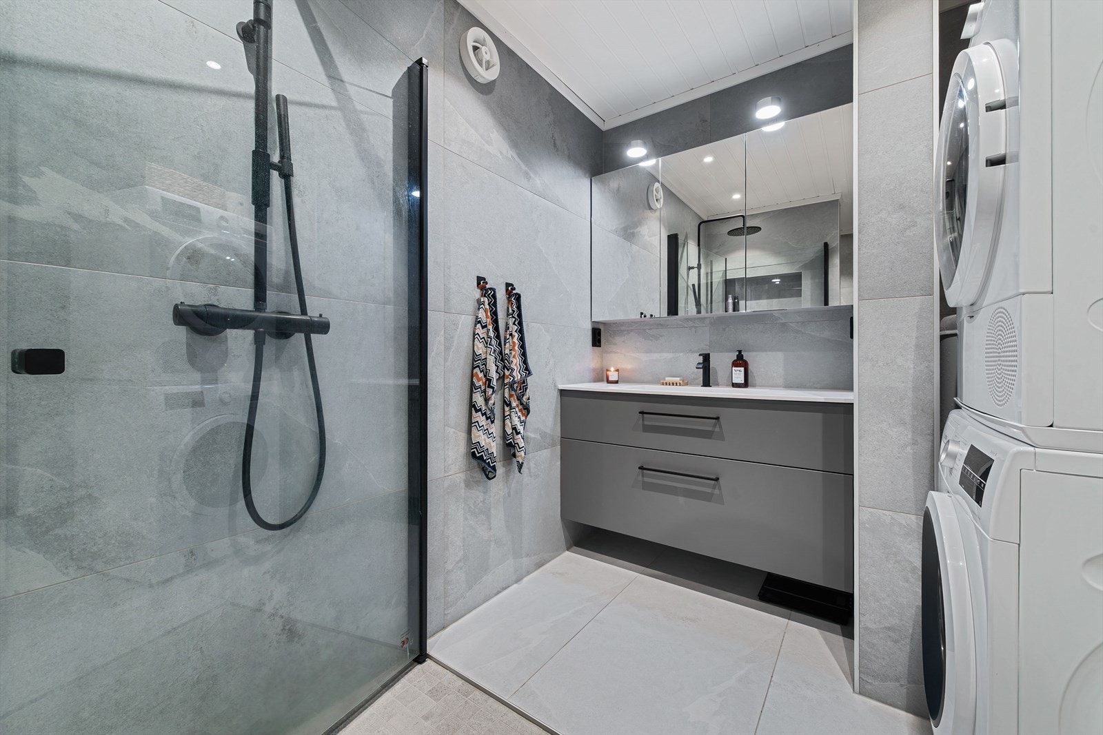 Rommet er innredet med heldekkende servant, speilskap med belysning, veggmontert toalett, innfeltbare dusjvegger/hjørne i herdet glass. Galleribilde