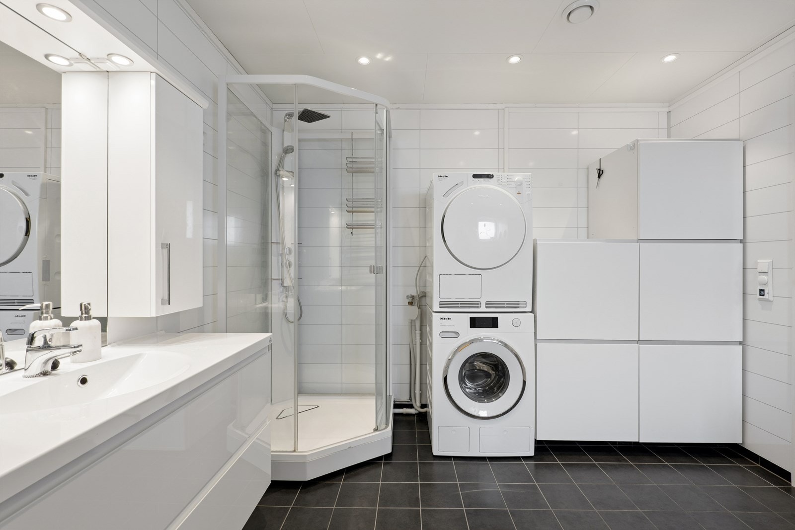 Bad/vaskerom i første etasje har flislagt gulv med elektriske varmekabler og baderomsplater på vegger. Galleribilde