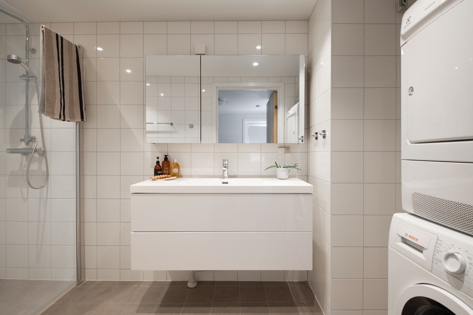 Moderne og stilrent bad fra 2024 med lyse, helflisede overflater og gulvvarme som gir god komfort året rundt. Opplegg til vaskemaskin. Galleribilde