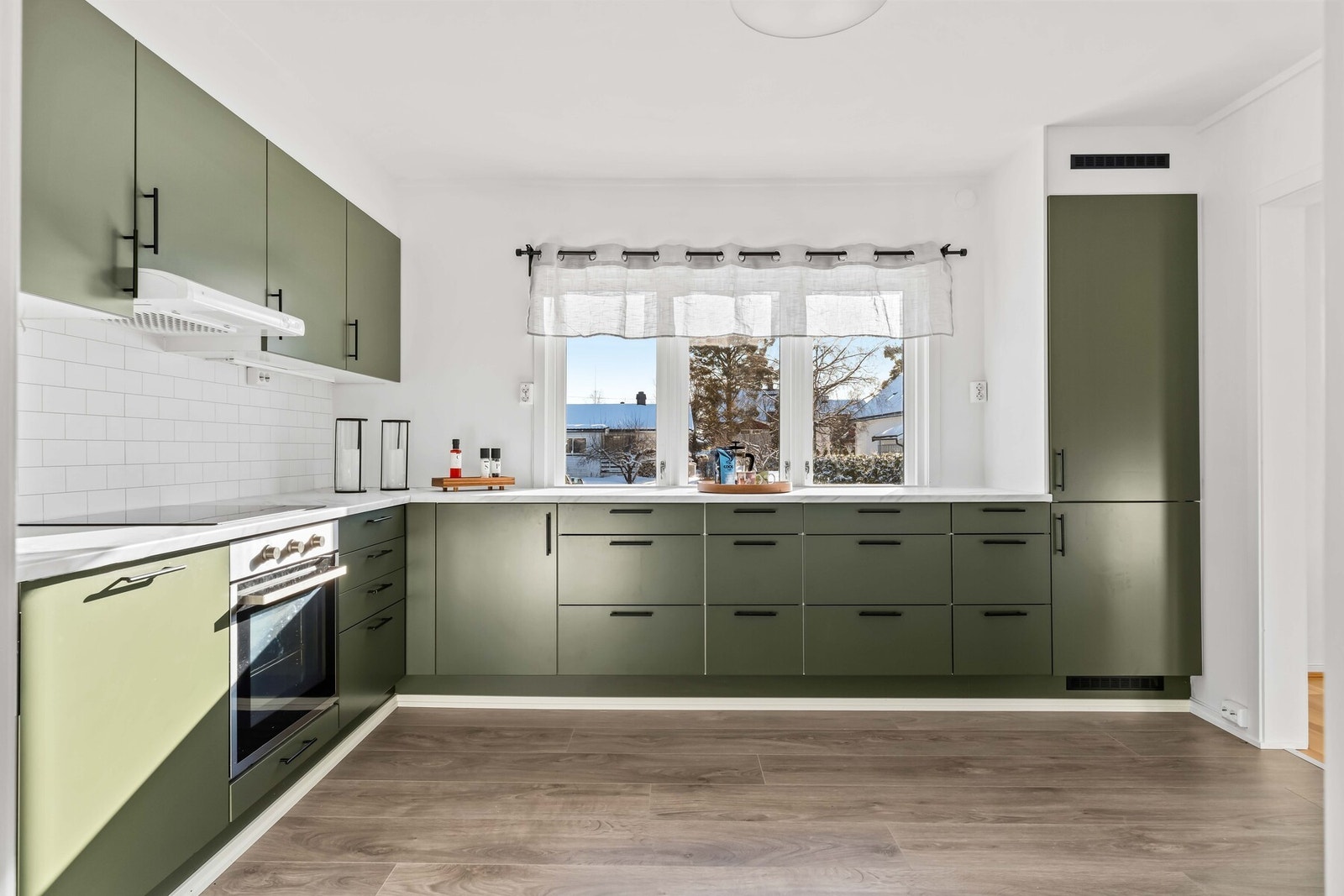 Innredningen har slette fronter med foring opp til tak og laminert benkeplate med nedfelt vaskekum. Mellom over- og underskap er det moderne flisimiterte Kitchenboards og belysning. Galleribilde