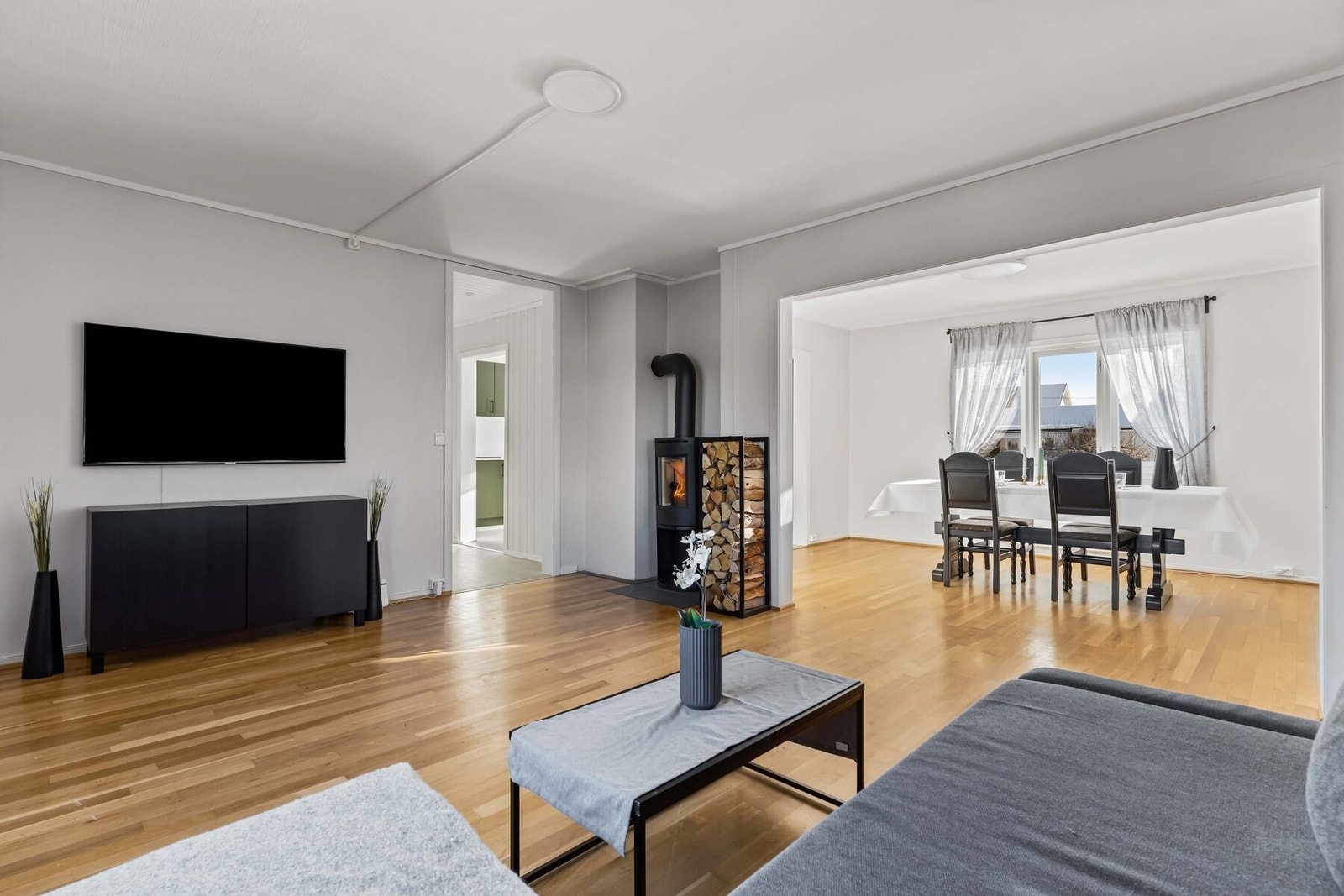 Koselig TV-stue med lysmalte veggflater og parkett på gulv, store vindusflater og god plass til sofa- og TV-løsning. Galleribilde