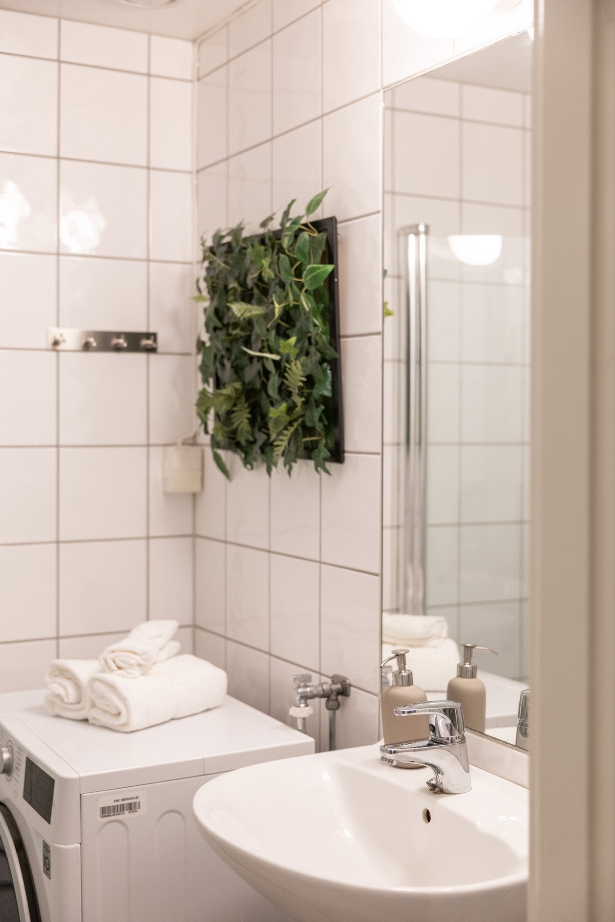 Badet er innredet med servant og speil, dusjhjørne med glassdører og opplegg for vaskemaskin. Galleribilde