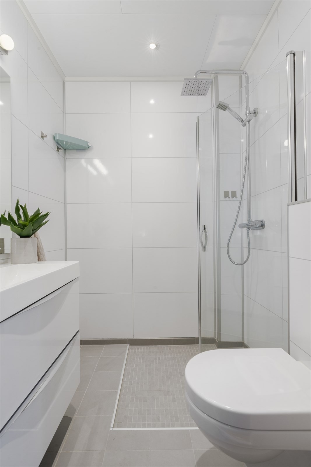 Badet er innredet med vegghengt wc, dusjhjørne med glassvegger og baderomsinnredning. Galleribilde