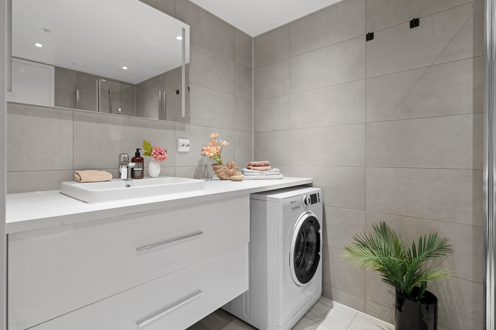 Badet er praktisk og funksjonelt innredet med vegghengt toalett, servant med ettgreps blandebatteri og skuffeinnredning, samt dusjhjørne med inn- og utadslående glassdører. Det er i tillegg opplegg for vaskemaskin Galleribilde