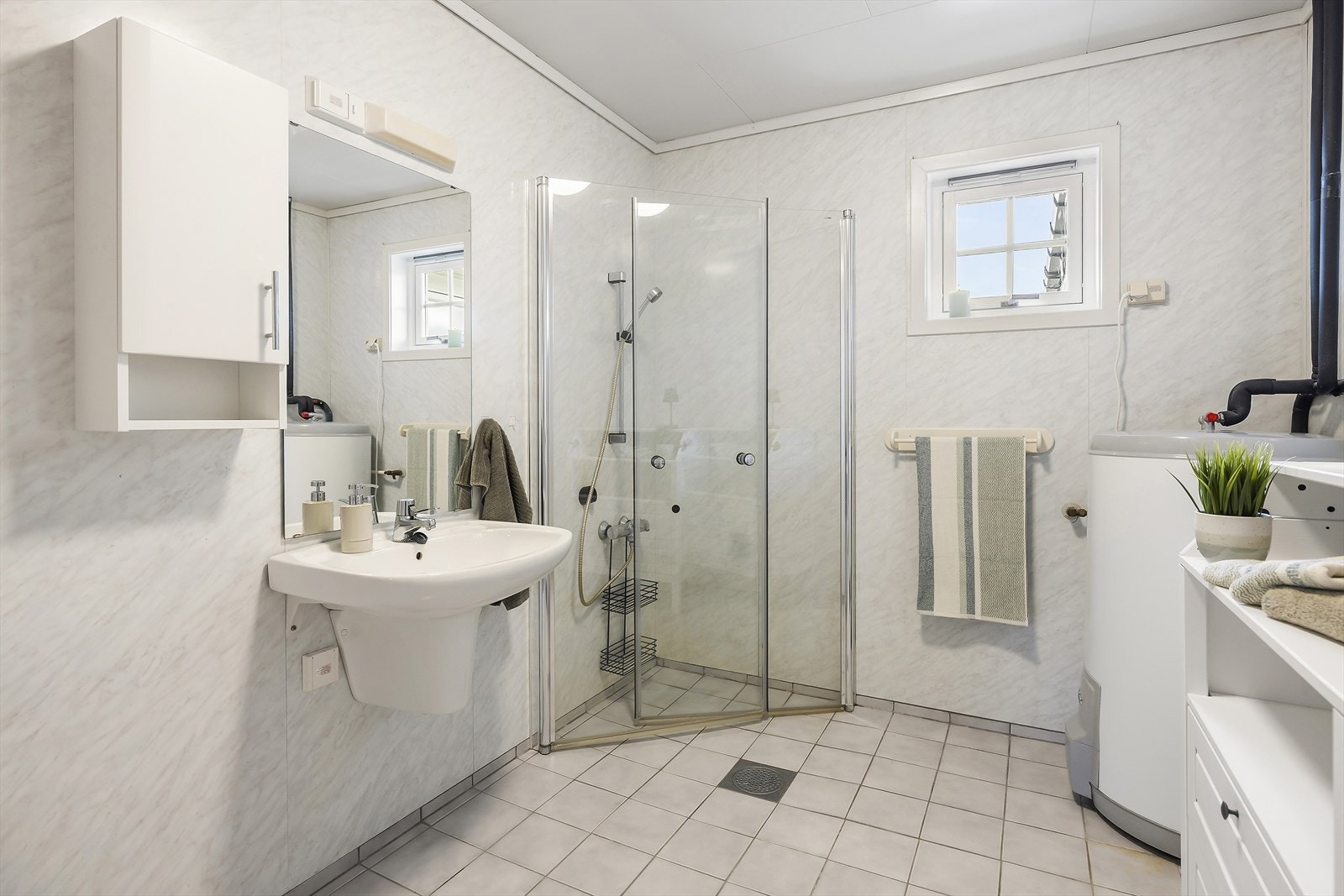 Badet i utleigedel er innreiia med dusj på vegg med innfellbare og plassbesparande dusjveggar, vegghengt servant og wc. Galleribilde