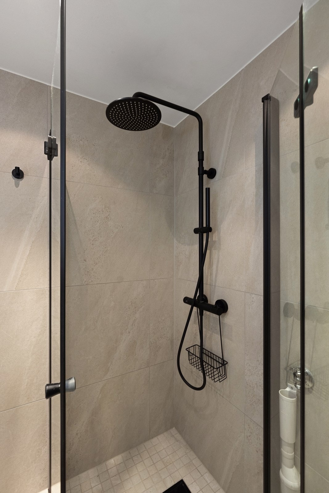 Rommet er innredet med veggfestet toalett, servant i helstøpt plate, dusj på gulv med dører i herdet glass og opplegg for vaskemaskin. Galleribilde