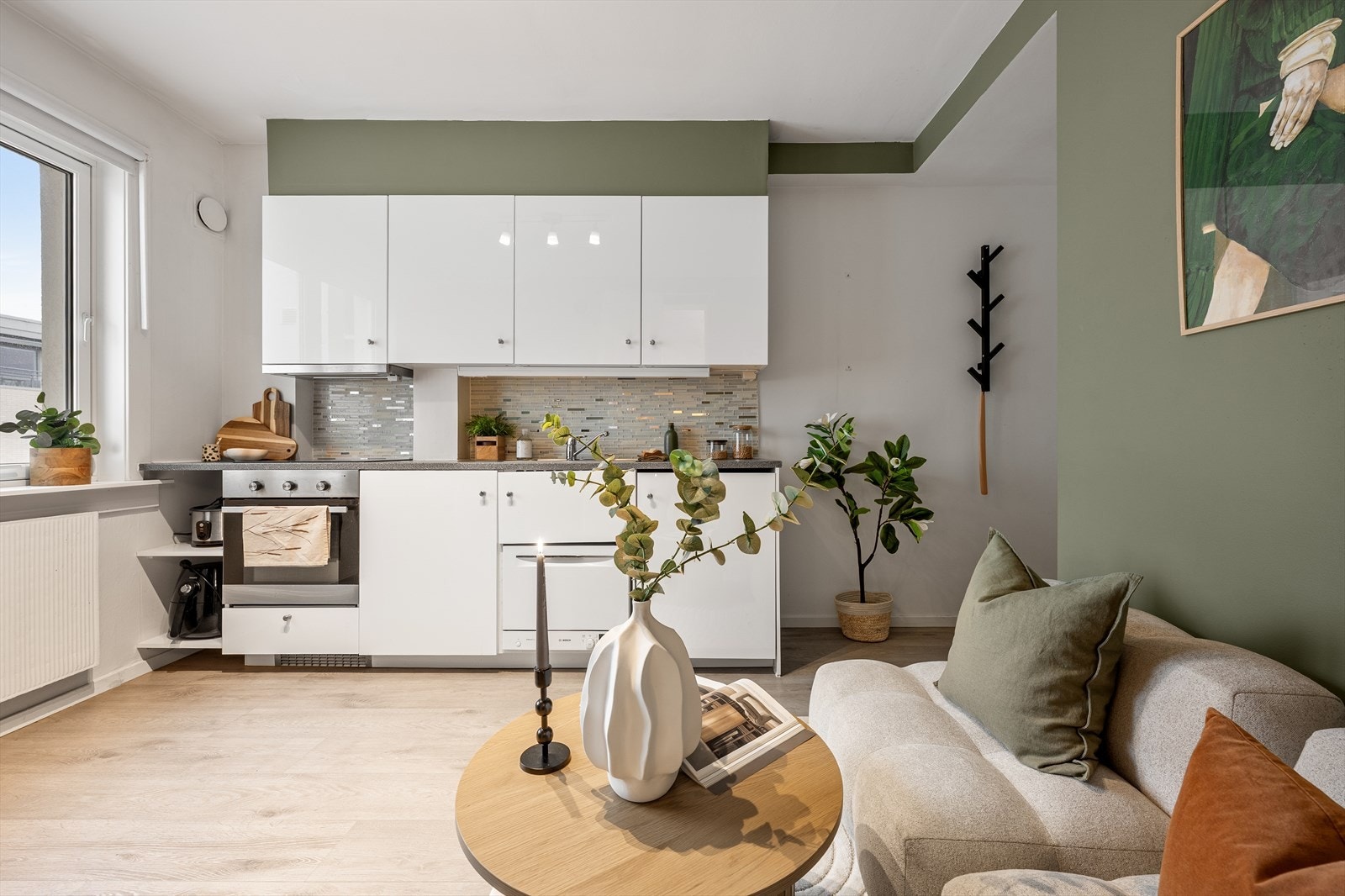 Høyglansfronter, laminat benkeplate m/fliser over, 1 ½ oppvaskkum, kjøkkenventilator i stål antatt m/kullfilter, integrert koketopp, stekeovn og kjøleskap under benk, samt frittstående hybel-oppvaskmaskin Galleribilde