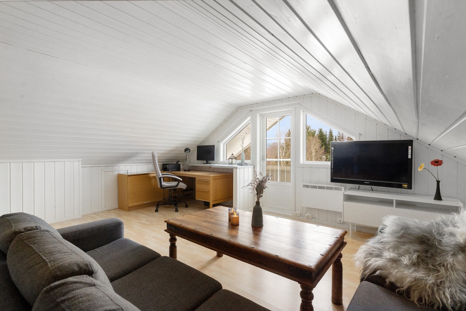 Koselig loftsstue med skråtak, sittegruppe og plass til hjemmekontor. Galleribilde