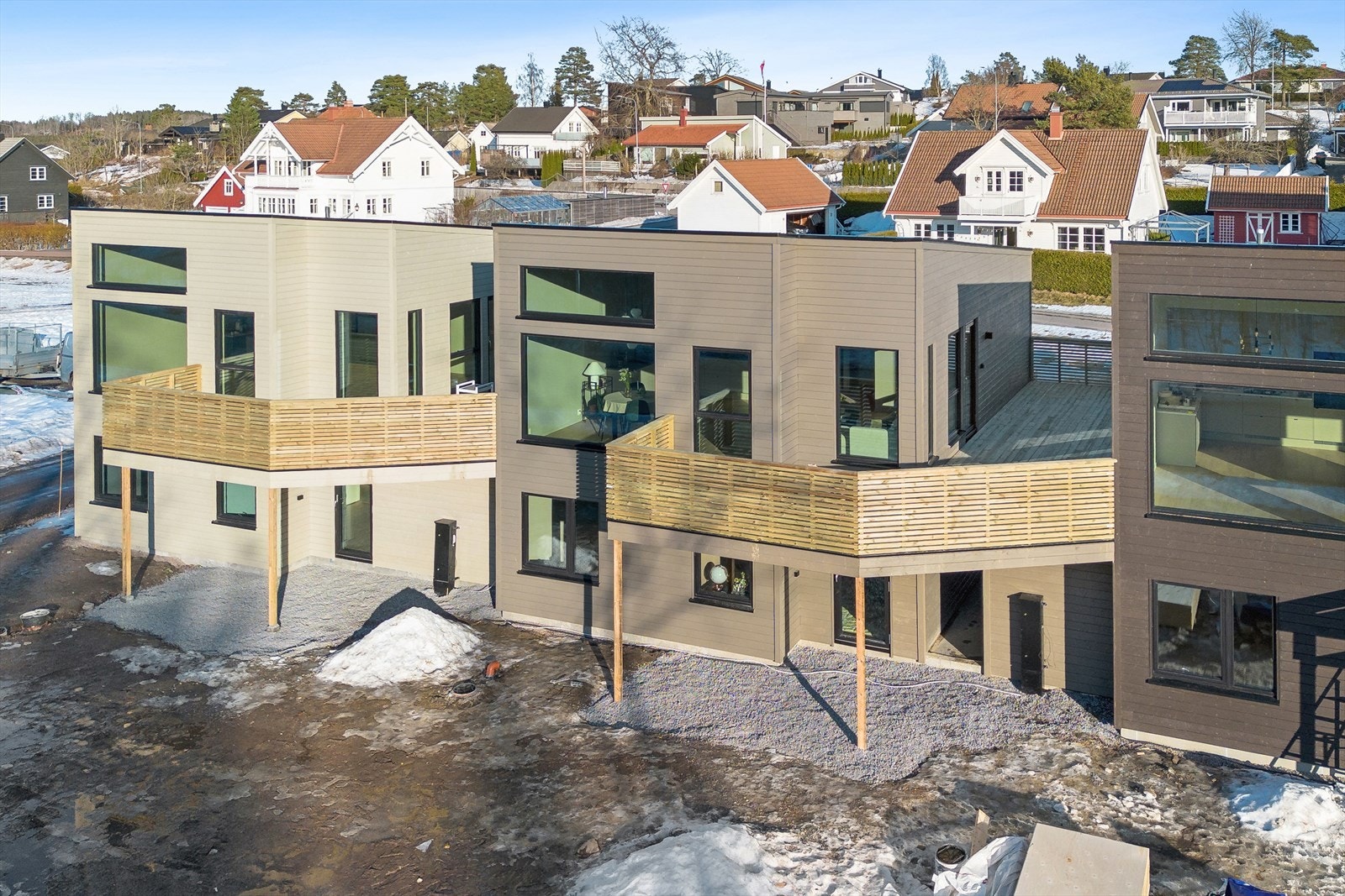 En enebolig i rekke med moderne arkitektur og en kombinasjon av trepanel og store vindusflater. Galleribilde