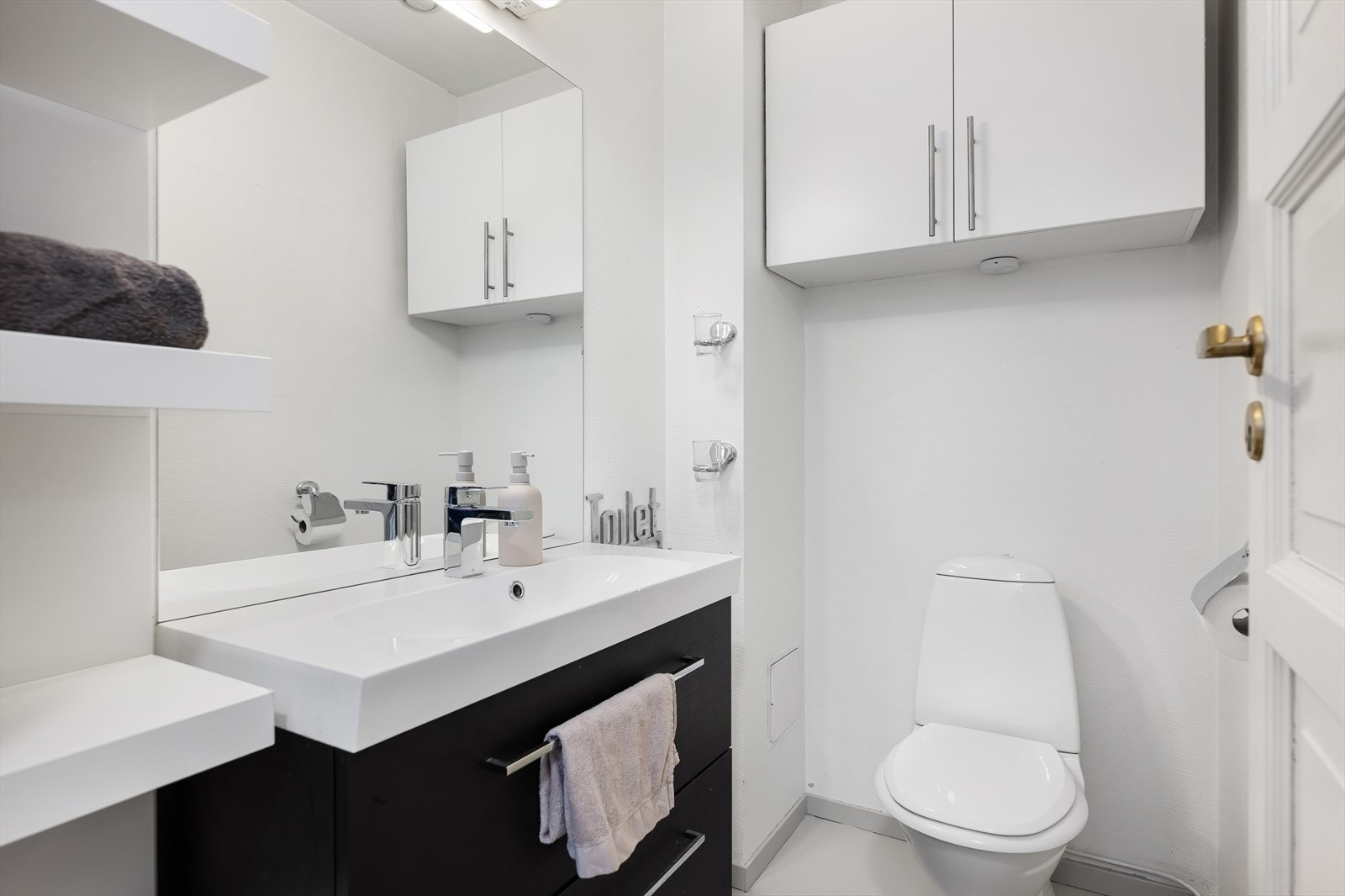 Praktisk toalettrom innredet med servant i møbel og toalett. Galleribilde